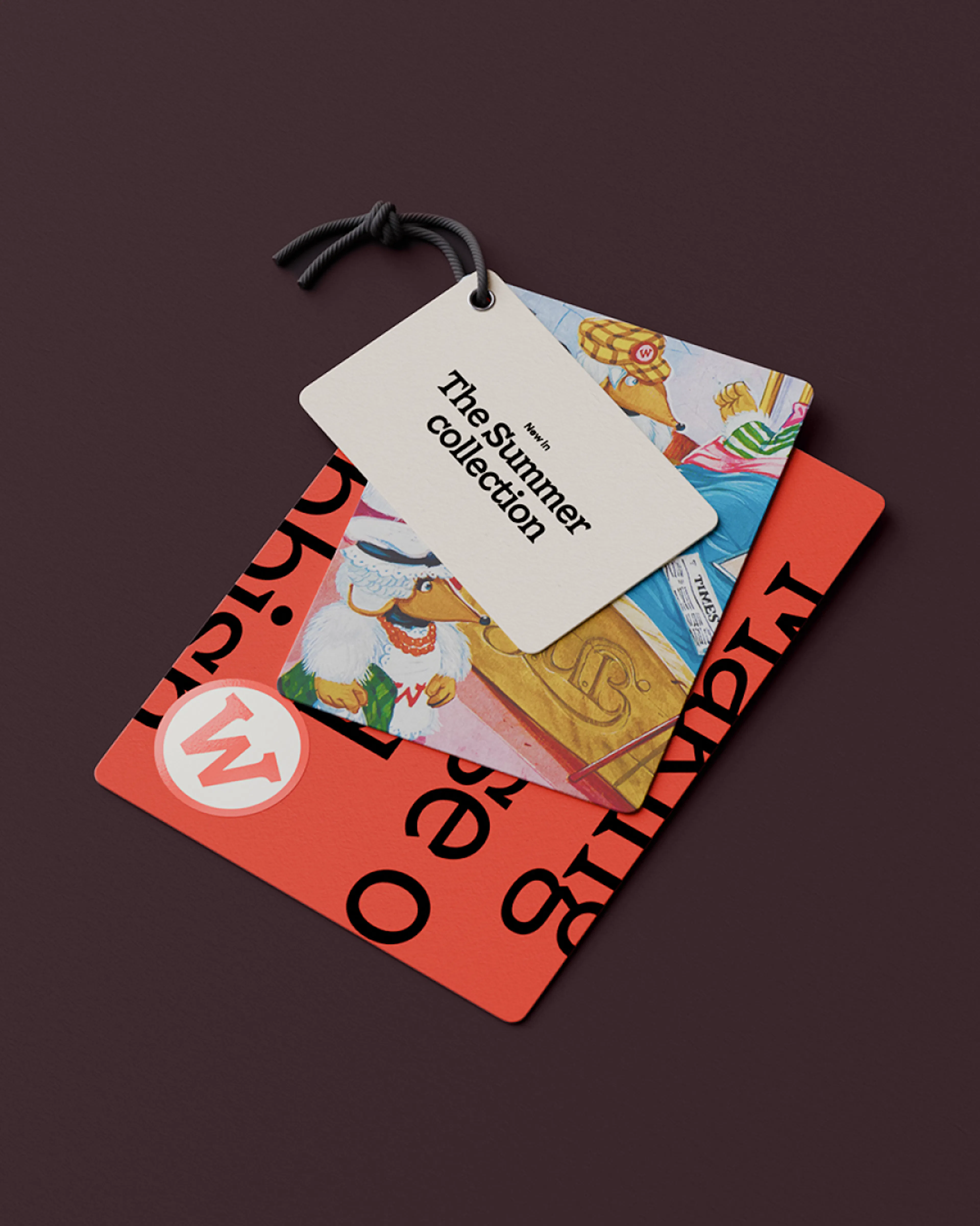 Layered Wombles swing tags on a dark plum background, a cream tag reading ‘The Summer Collection’ over a red tag with the W logo and Womble illustrations