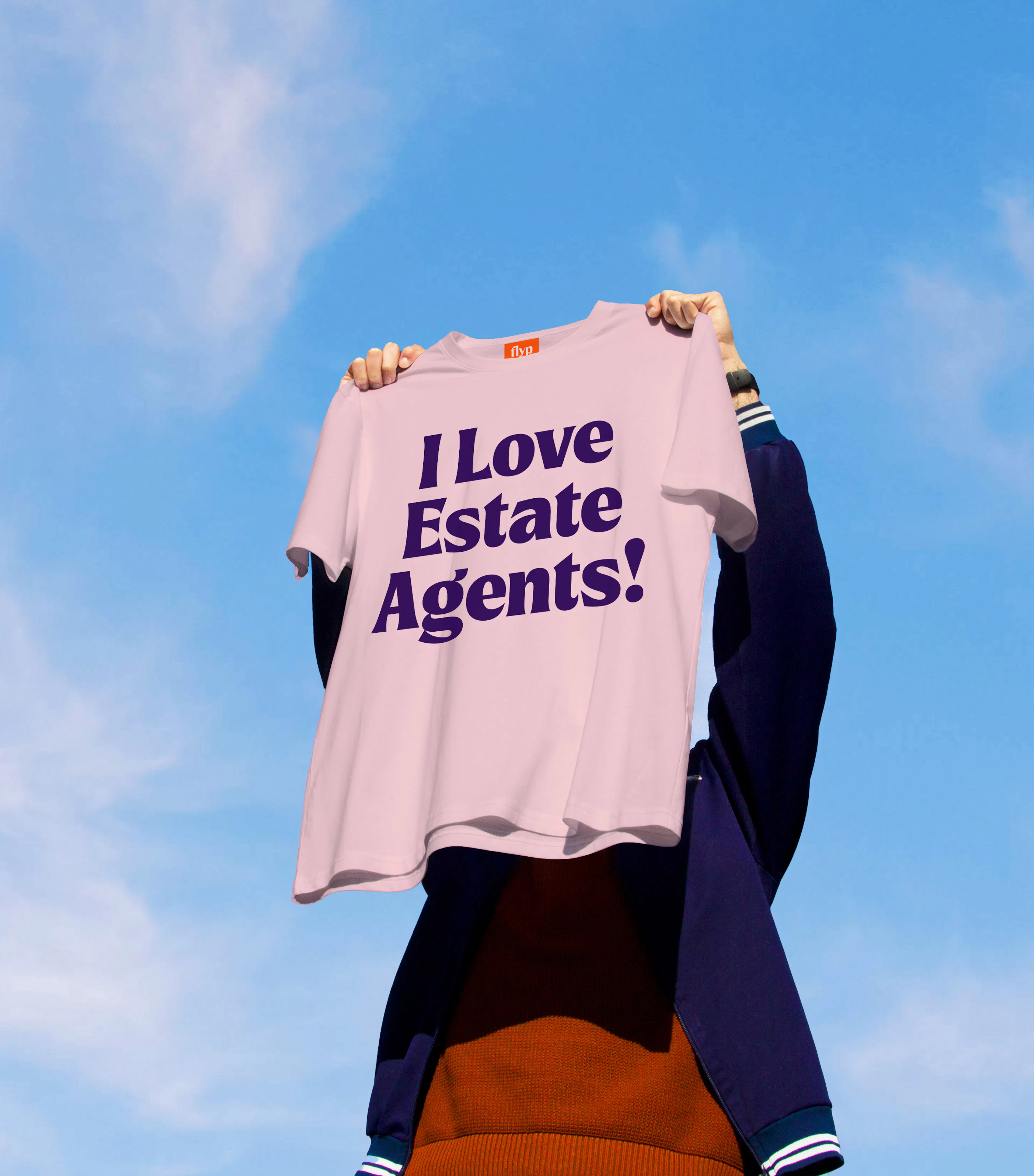 Person holding up a pink T-shirt reading 'I Love Estate Agents!' against a blue sky