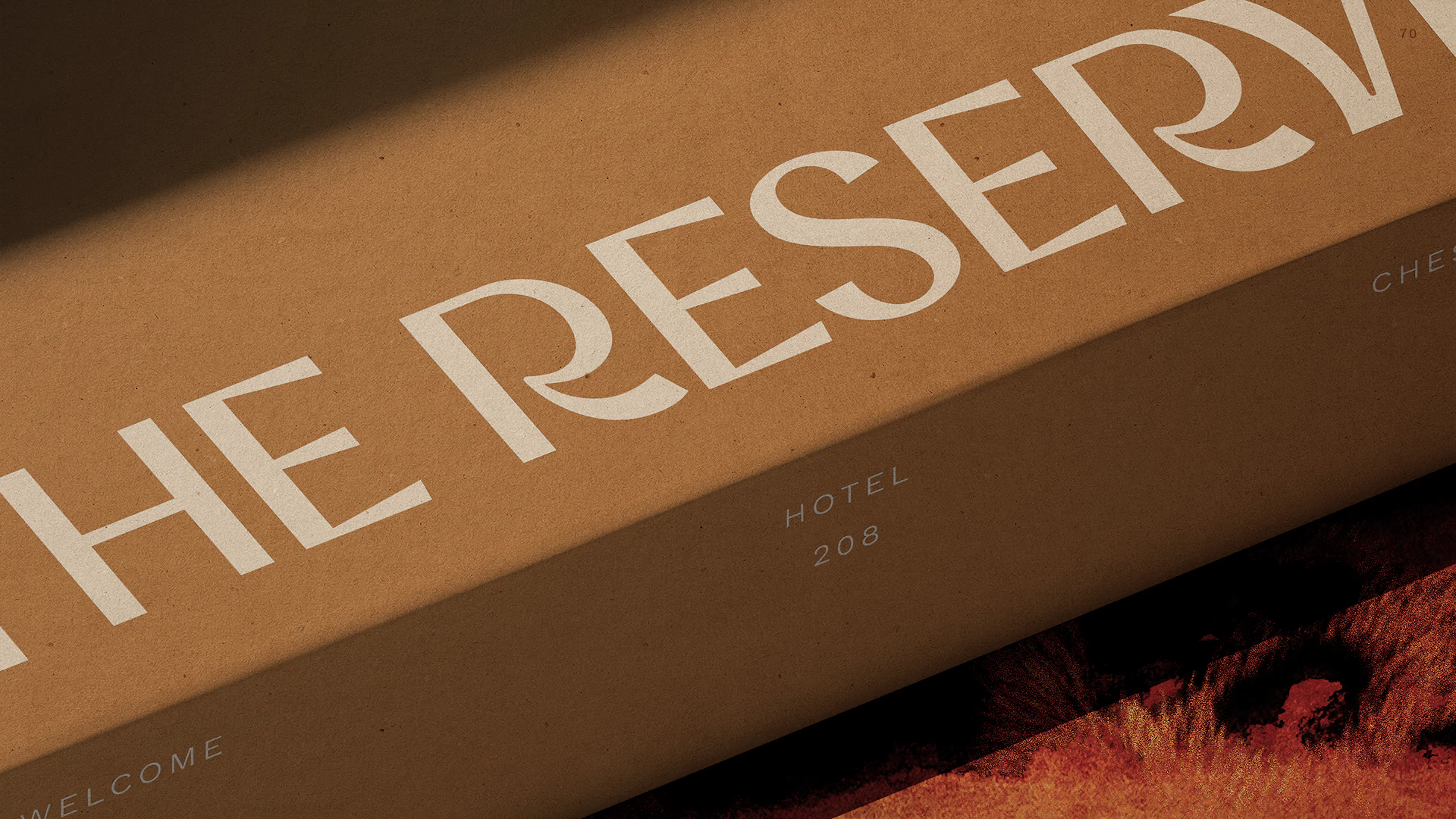 Close-up of a kraft welcome box printed with 'The Reserve' in cream lettering, resting on an animal-print surface