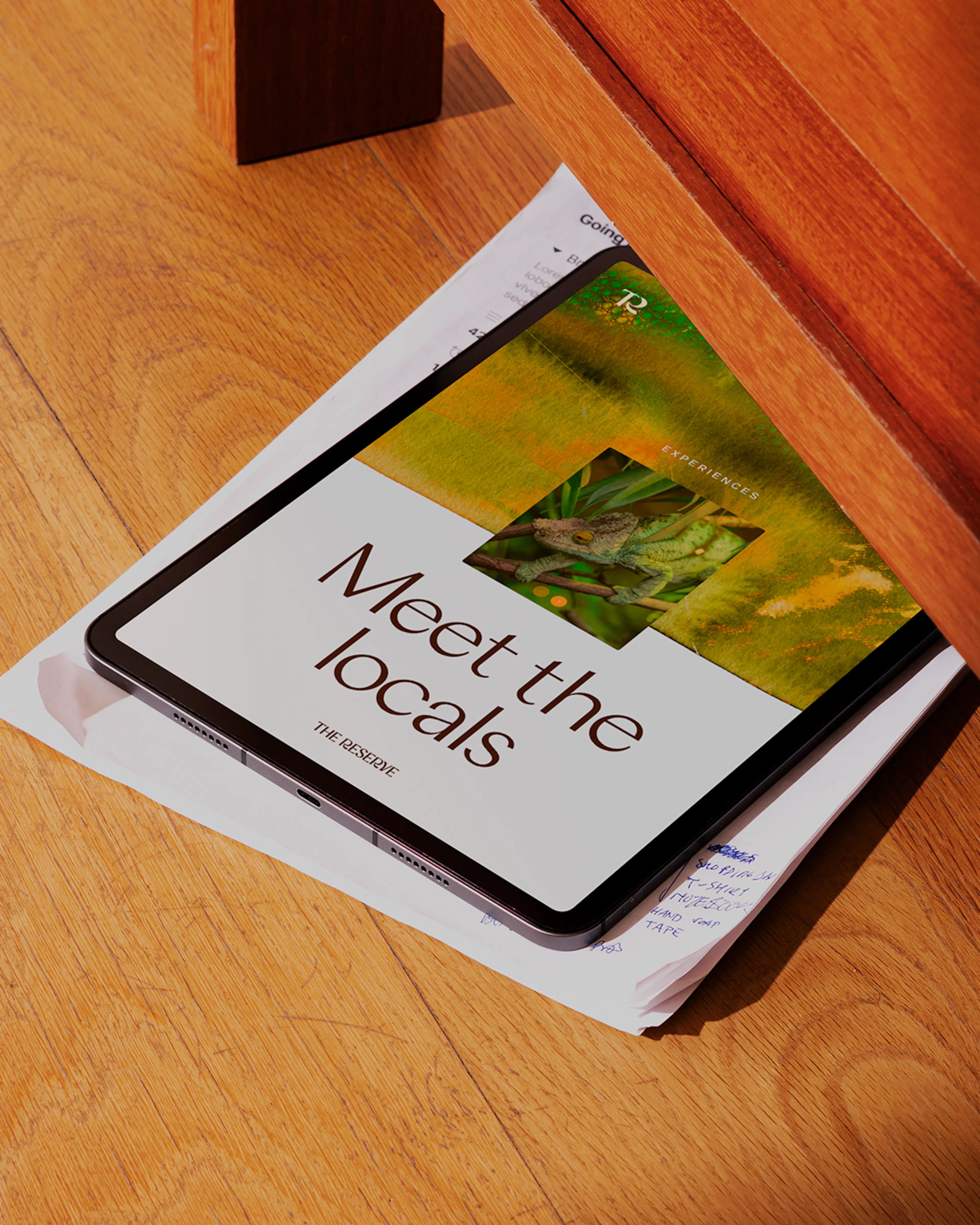 Tablet on a wooden floor showing a 'Meet the locals' screen with a bird photo
