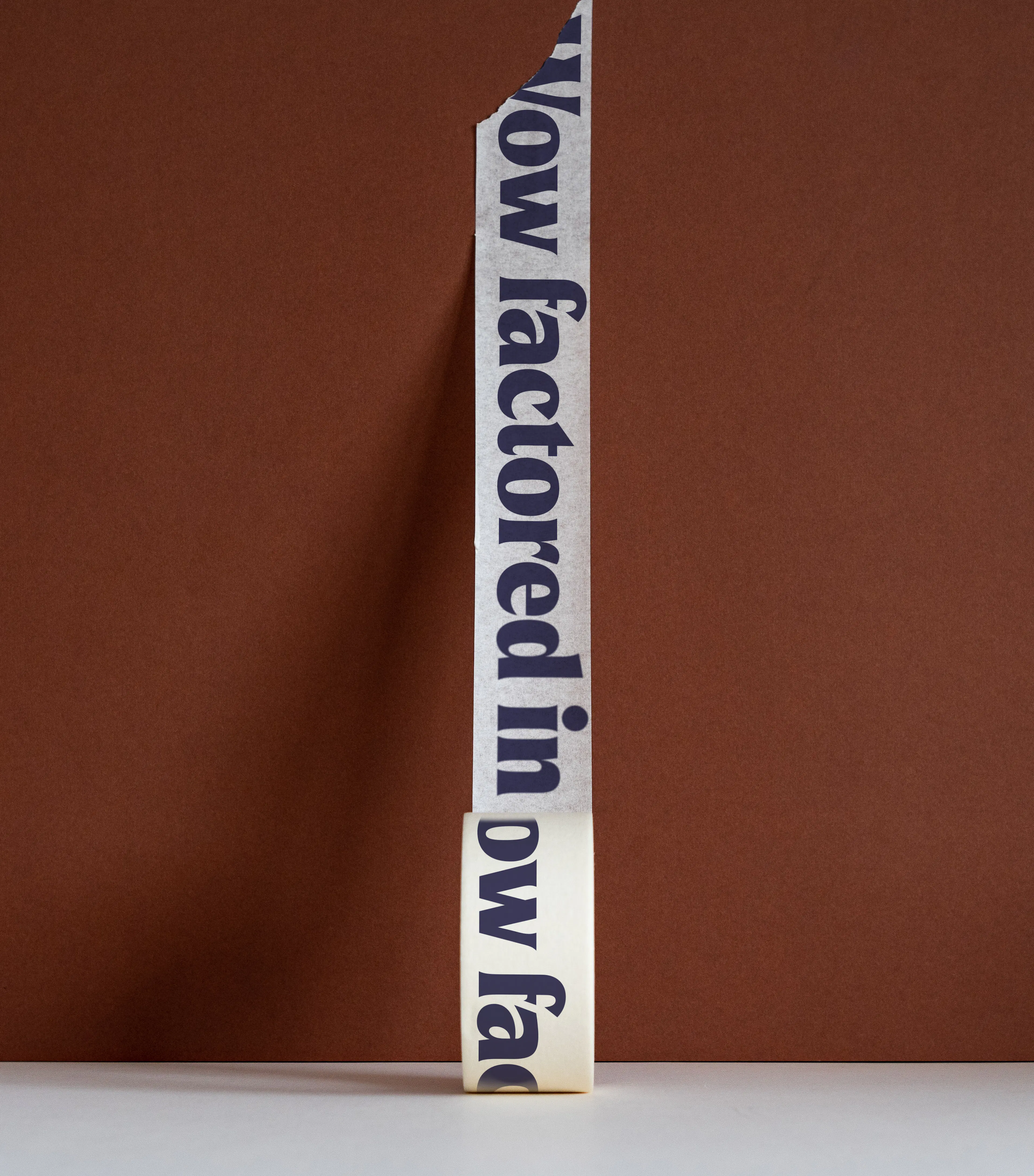 Strip of paper printed with flyp copy, standing against a terracotta wall