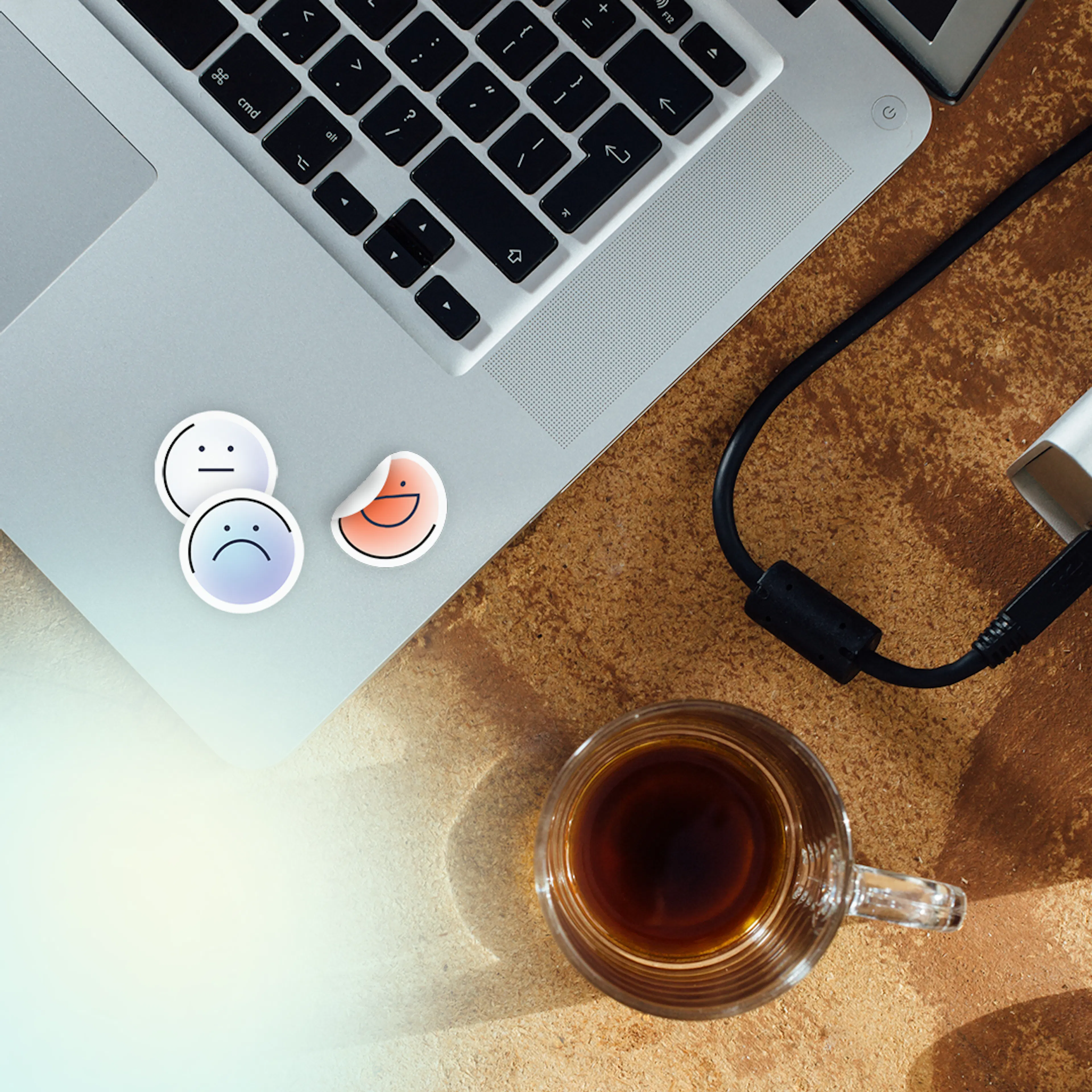 Hotjar emotion stickers on a laptop beside a glass of tea