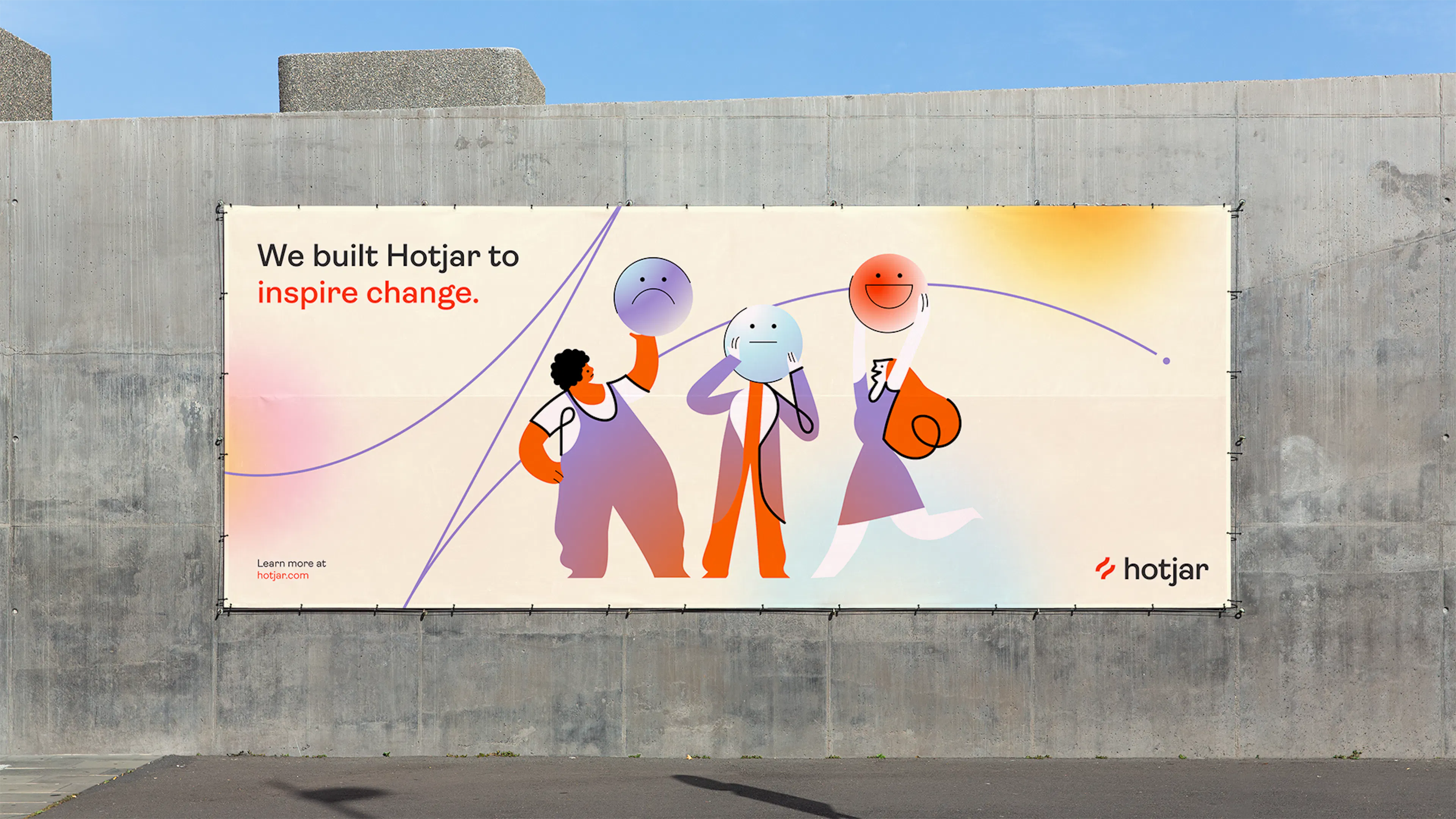 Hotjar billboard on a concrete wall reading 'We built Hotjar to inspire change', with three illustrated characters