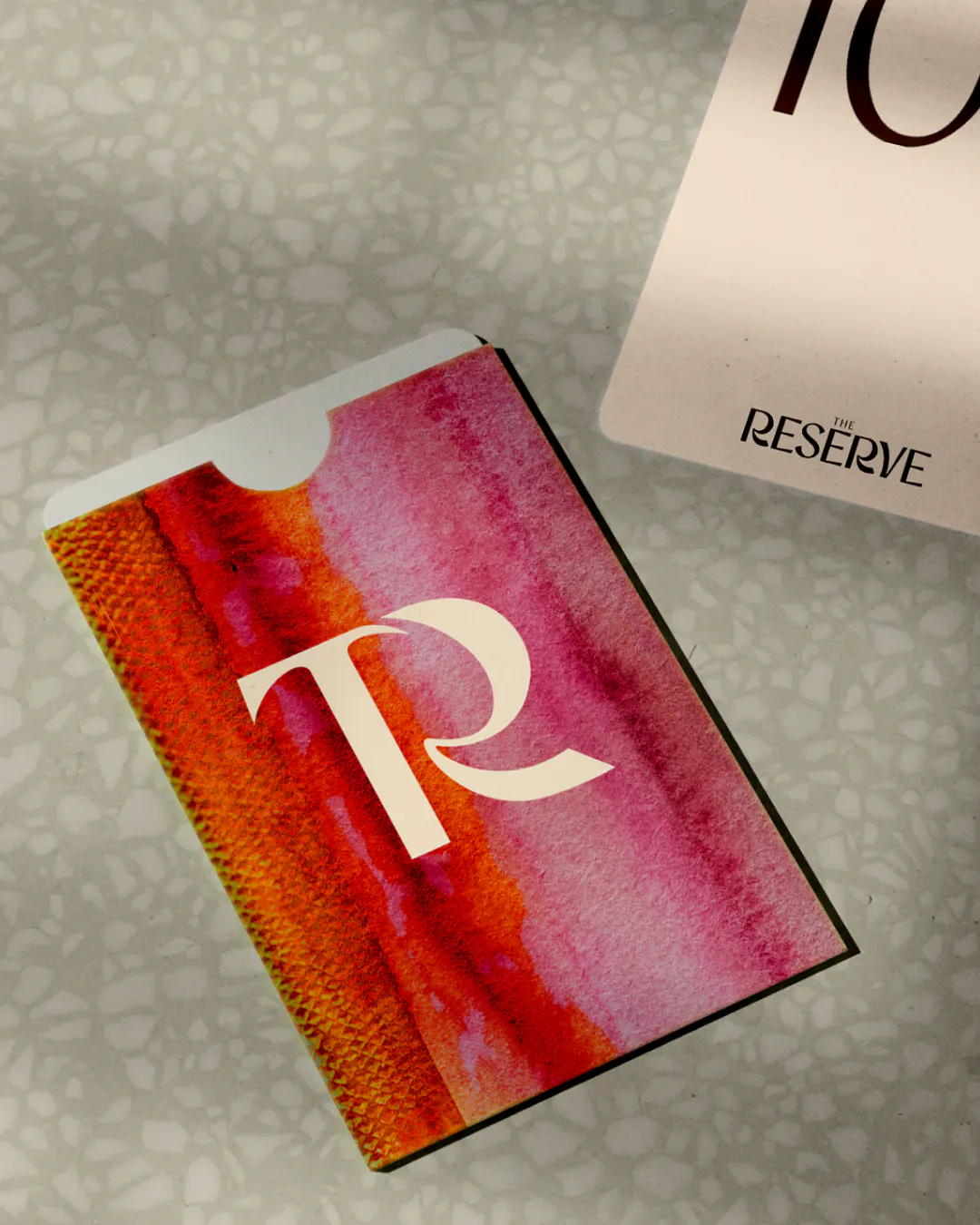 Room key card in a pink and orange watercolour sleeve with the TR monogram, beside a room number card