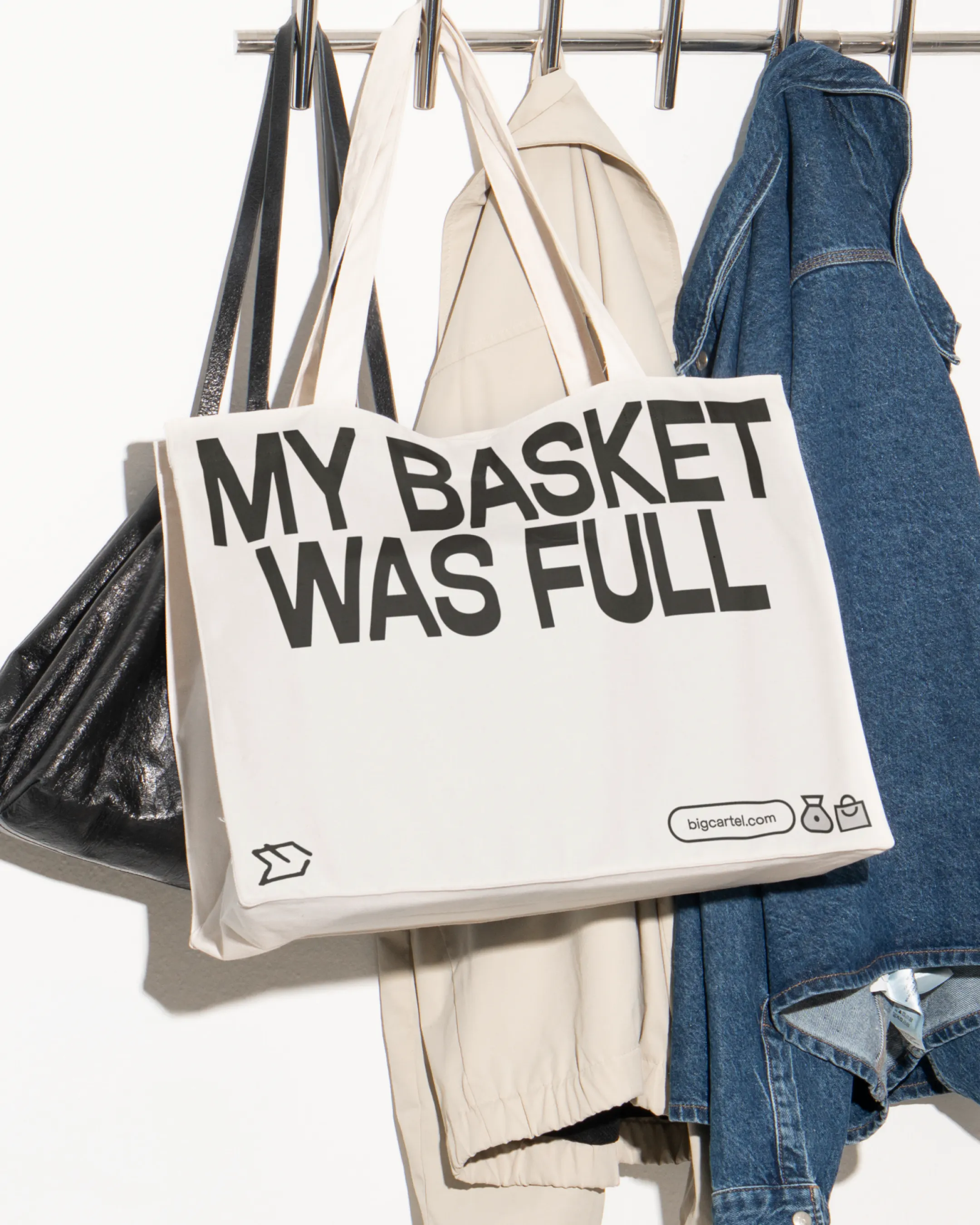 Big Cartel tote bag reading 'My basket was full' hanging on a coat rail