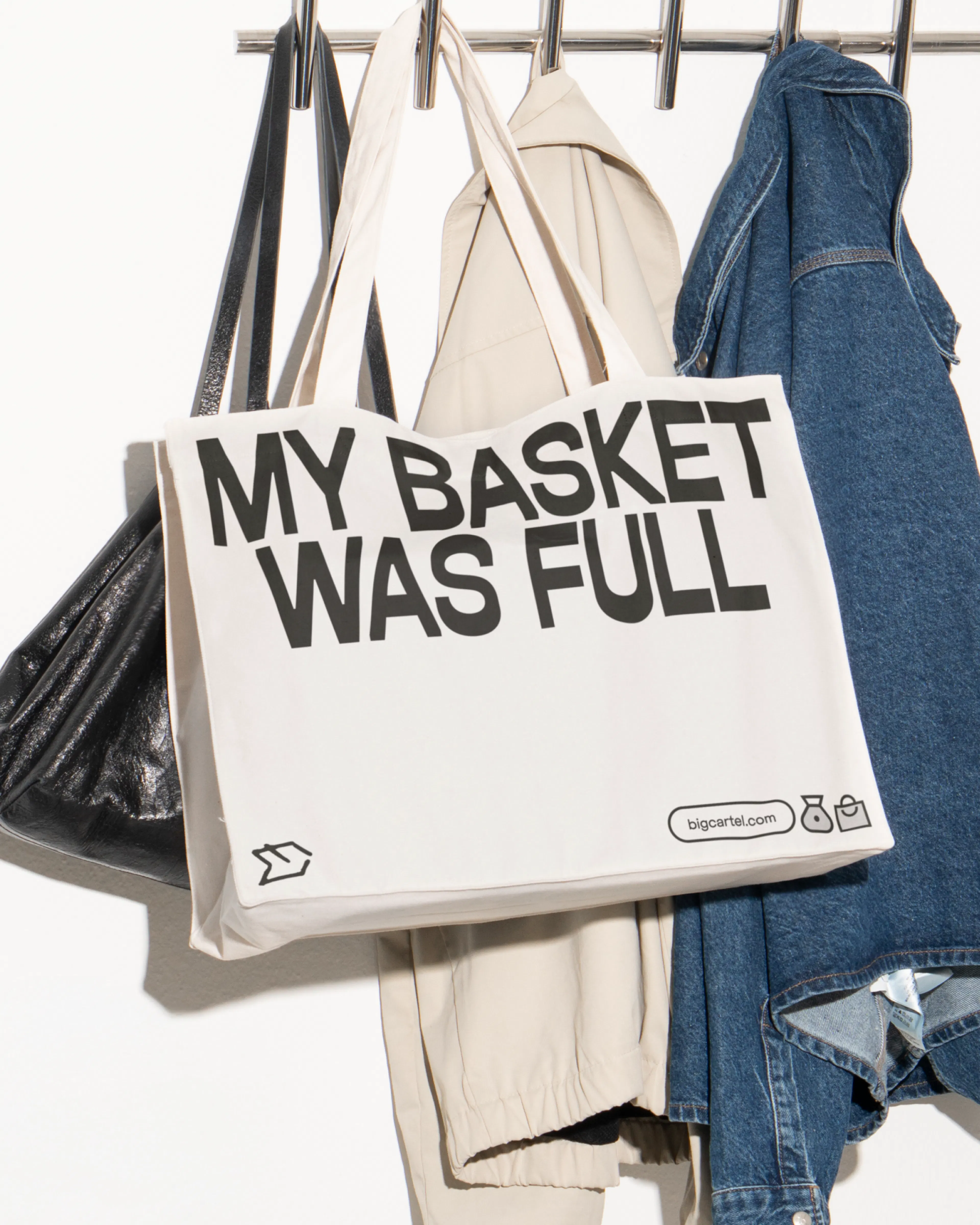 Big Cartel tote bag reading 'My basket was full' hanging on a coat rail
