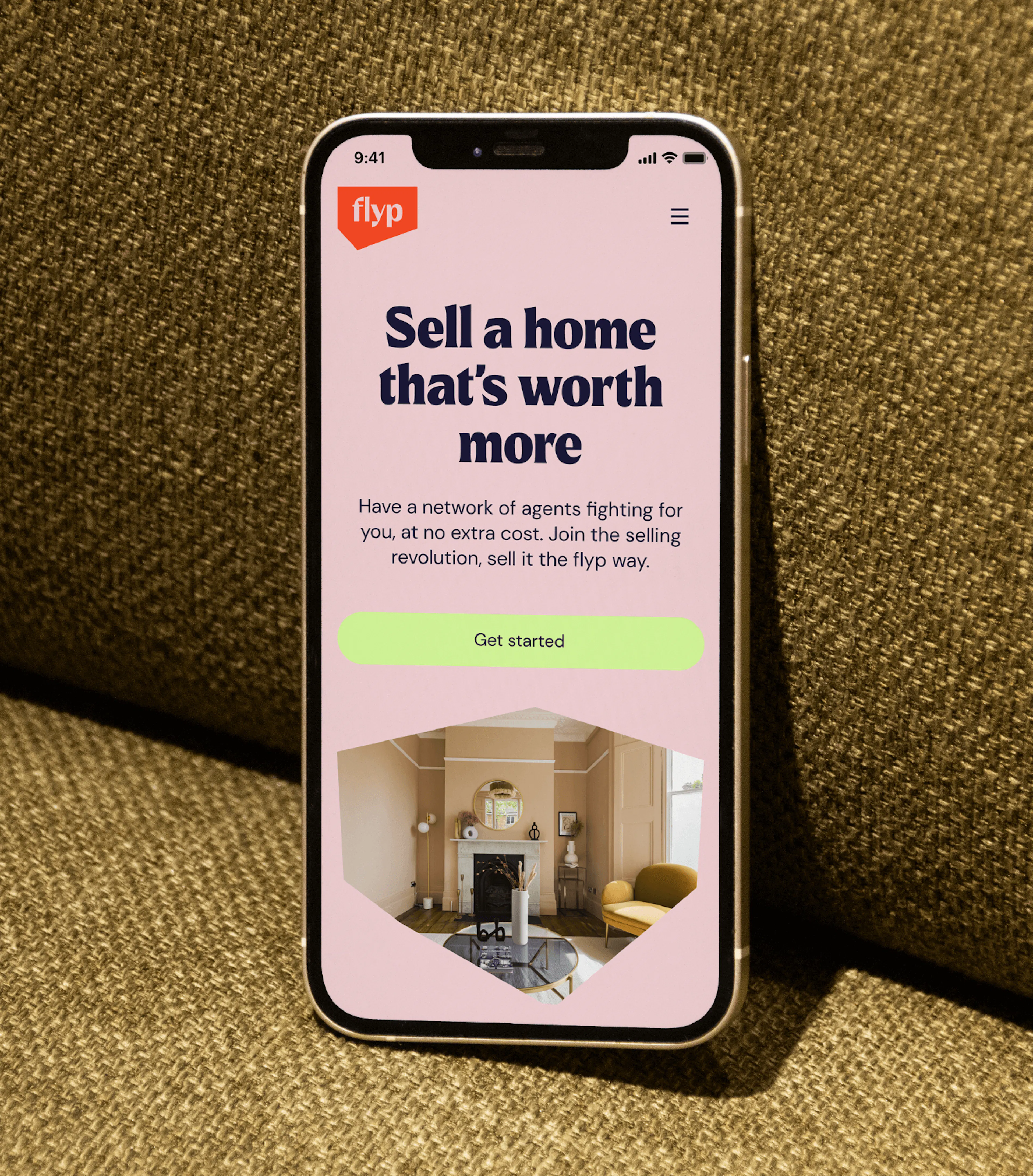 Phone displaying flyp’s home-selling app on a textured sofa