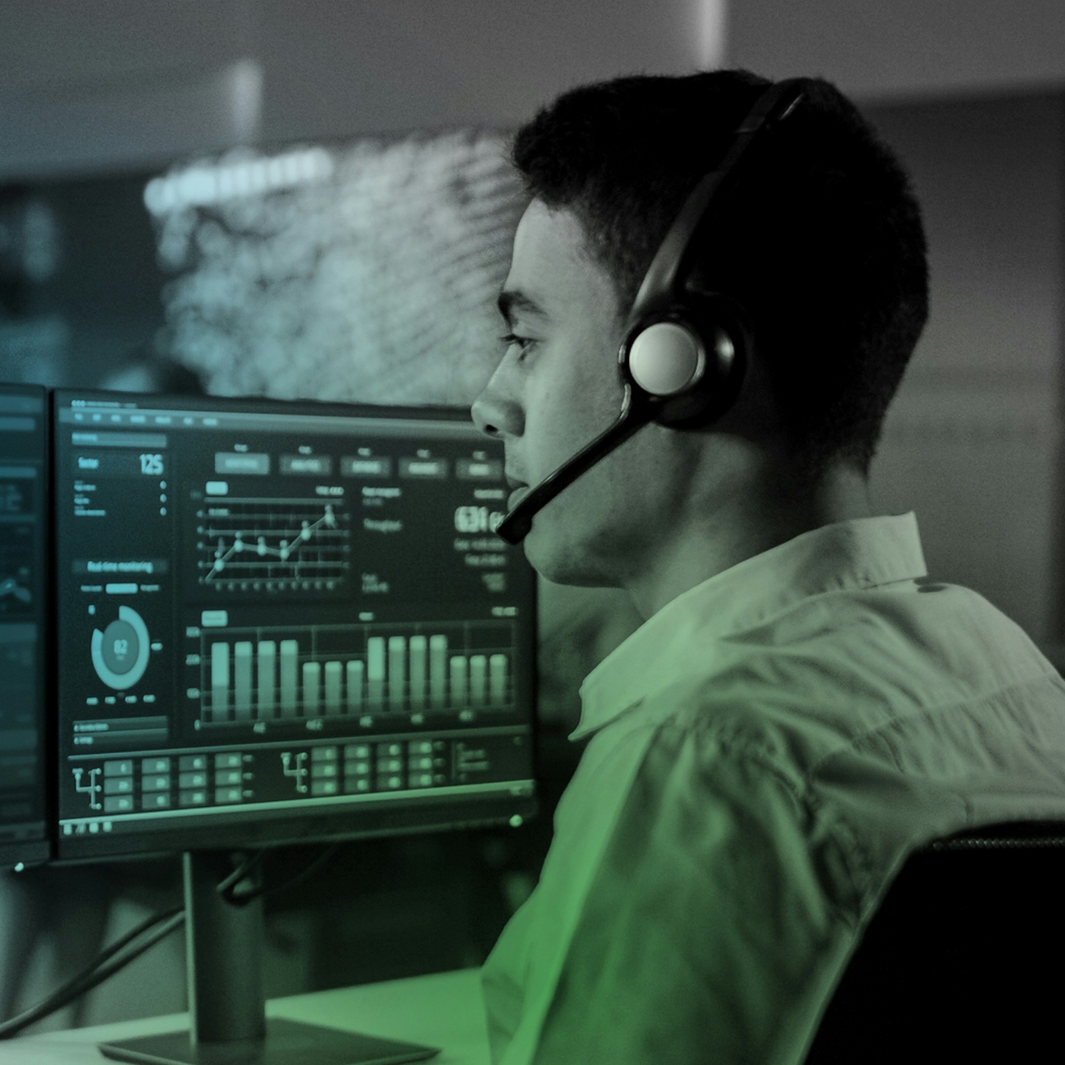 Un homme devant deux écrans d'ordinateur analysant des données affichées sous forme de graphiques.