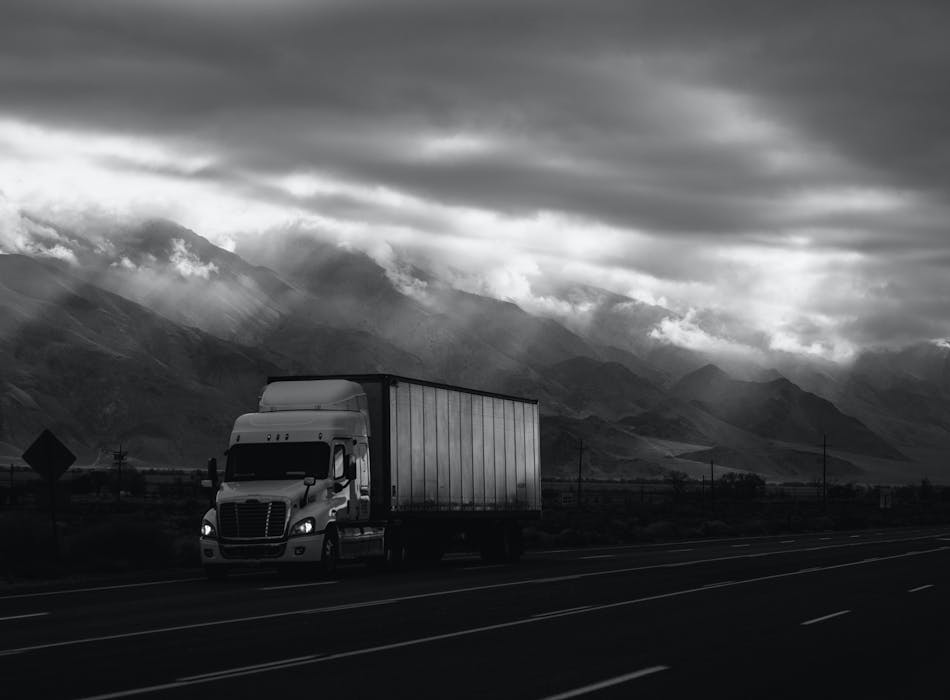 Black and white image of a truck on a motorway. Photo by Robson Hatsukami Morgan on Unsplash