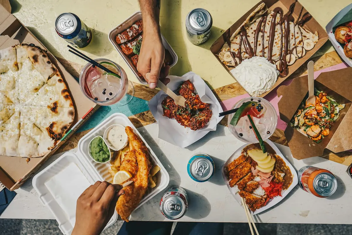 An overhead shot of a table laden with an assortment of takeout food, showcasing a diverse range of culinary options that could represent a modern, eclectic "box lunch.