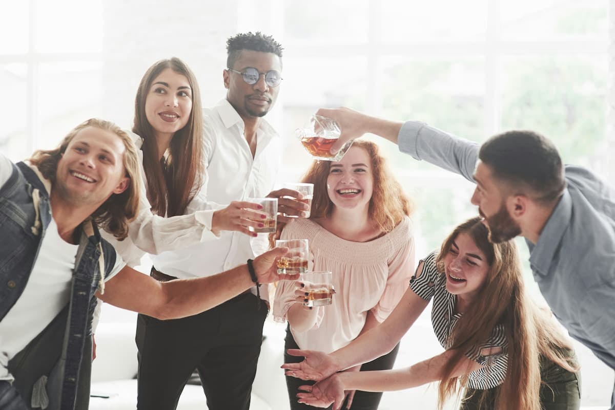 A group of friends smiling and toasting with glasses of drinks in a relaxed celebration