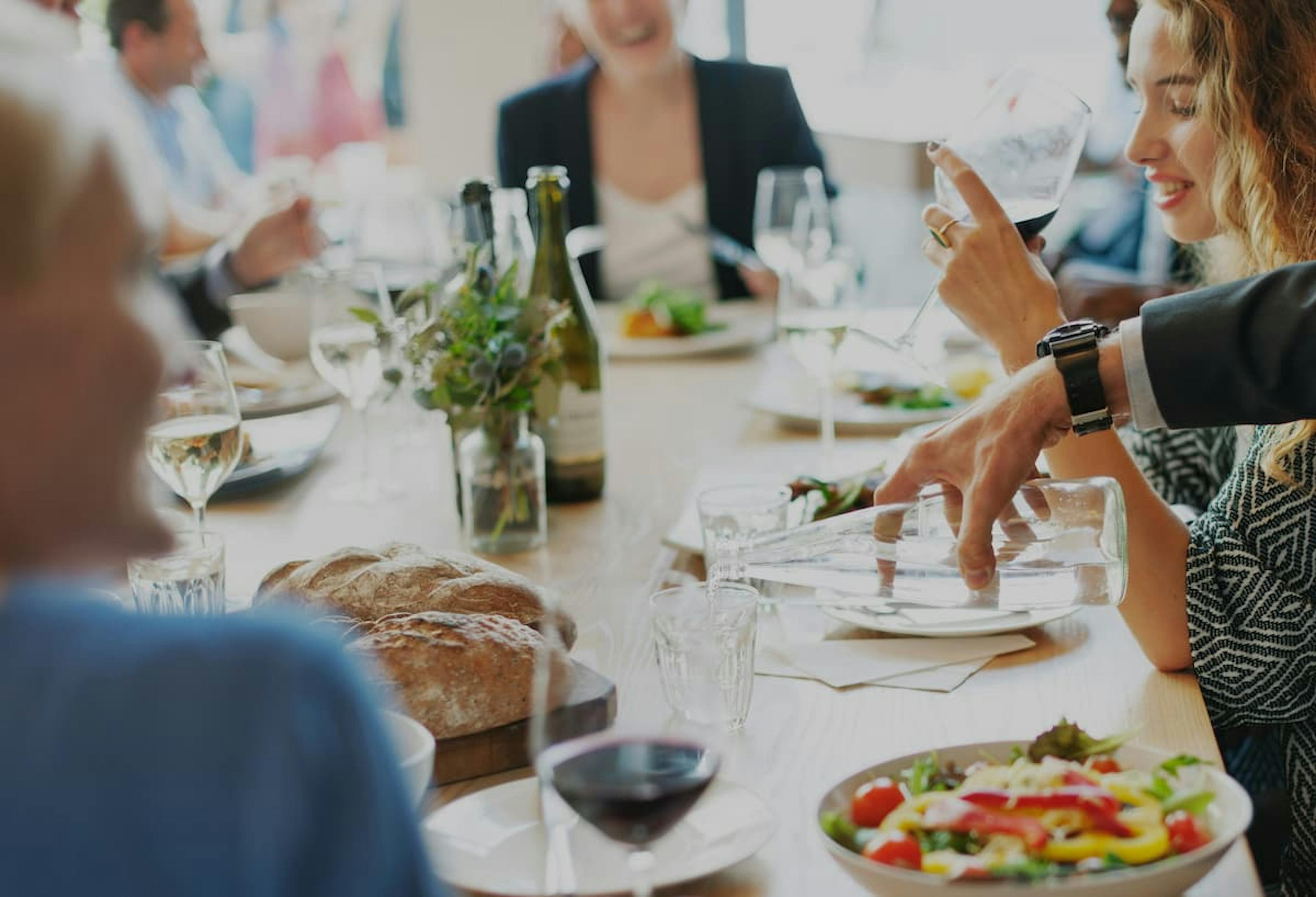 A group of people enjoying a lunch with a variety of dishes, including salad and bread, in a relaxed office environment