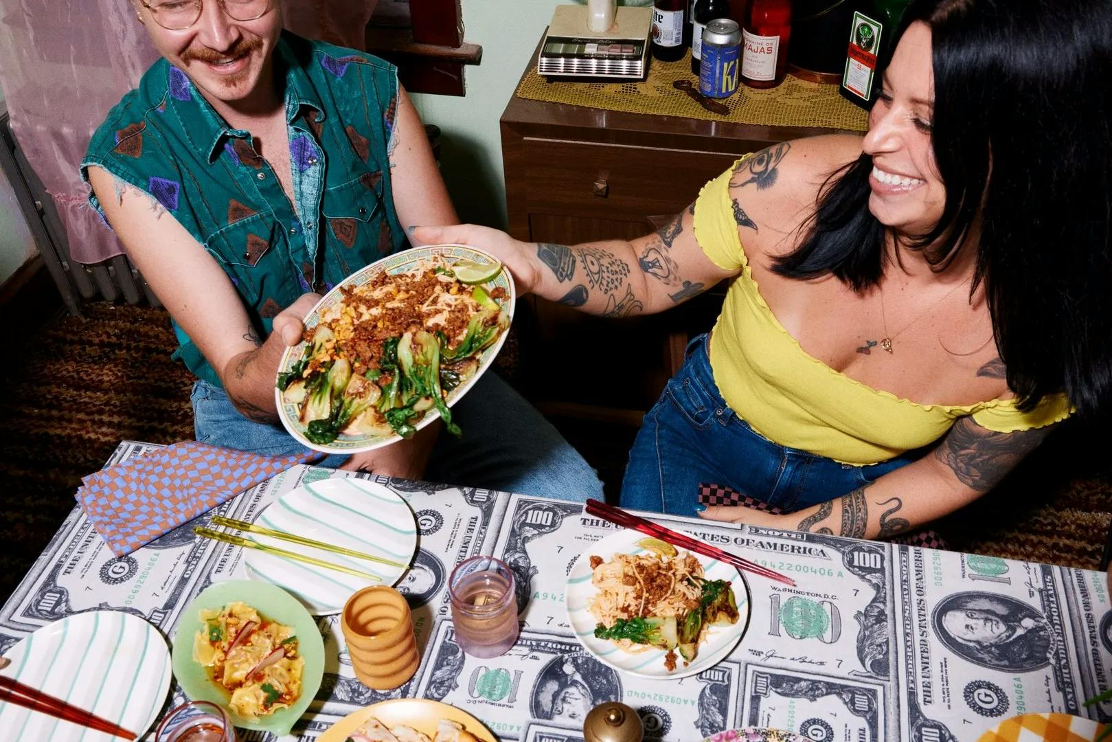 A couple enjoying a meal at a restaurant. They are both holding the same plate.