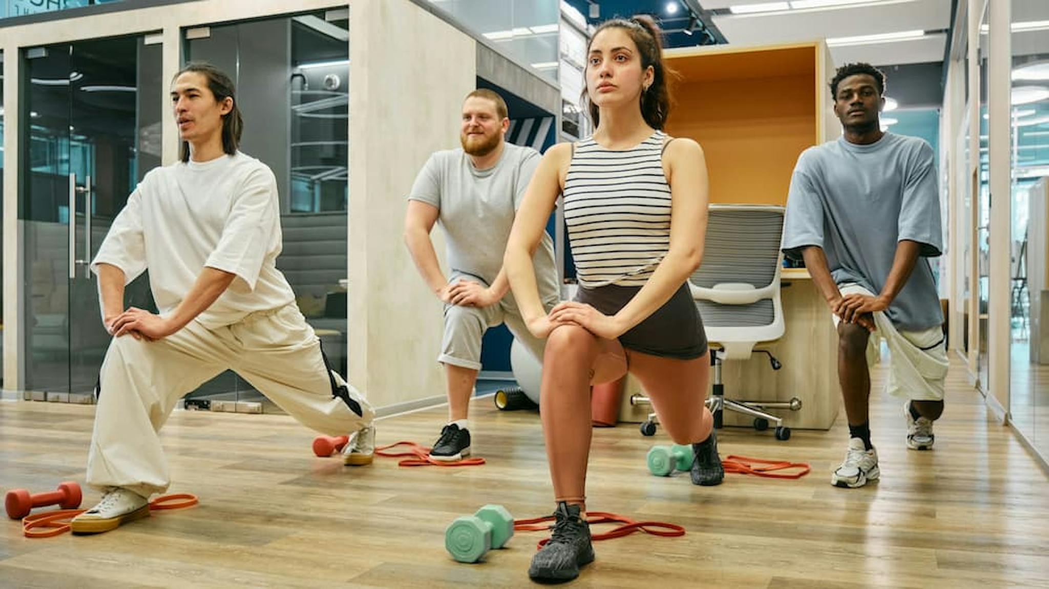 A diverse group of people performing stretching exercises in a modern gym environment, promoting well-being and physical activity