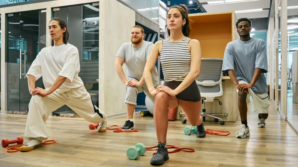 A diverse group of people performing stretching exercises in a modern gym environment, promoting well-being and physical activity
