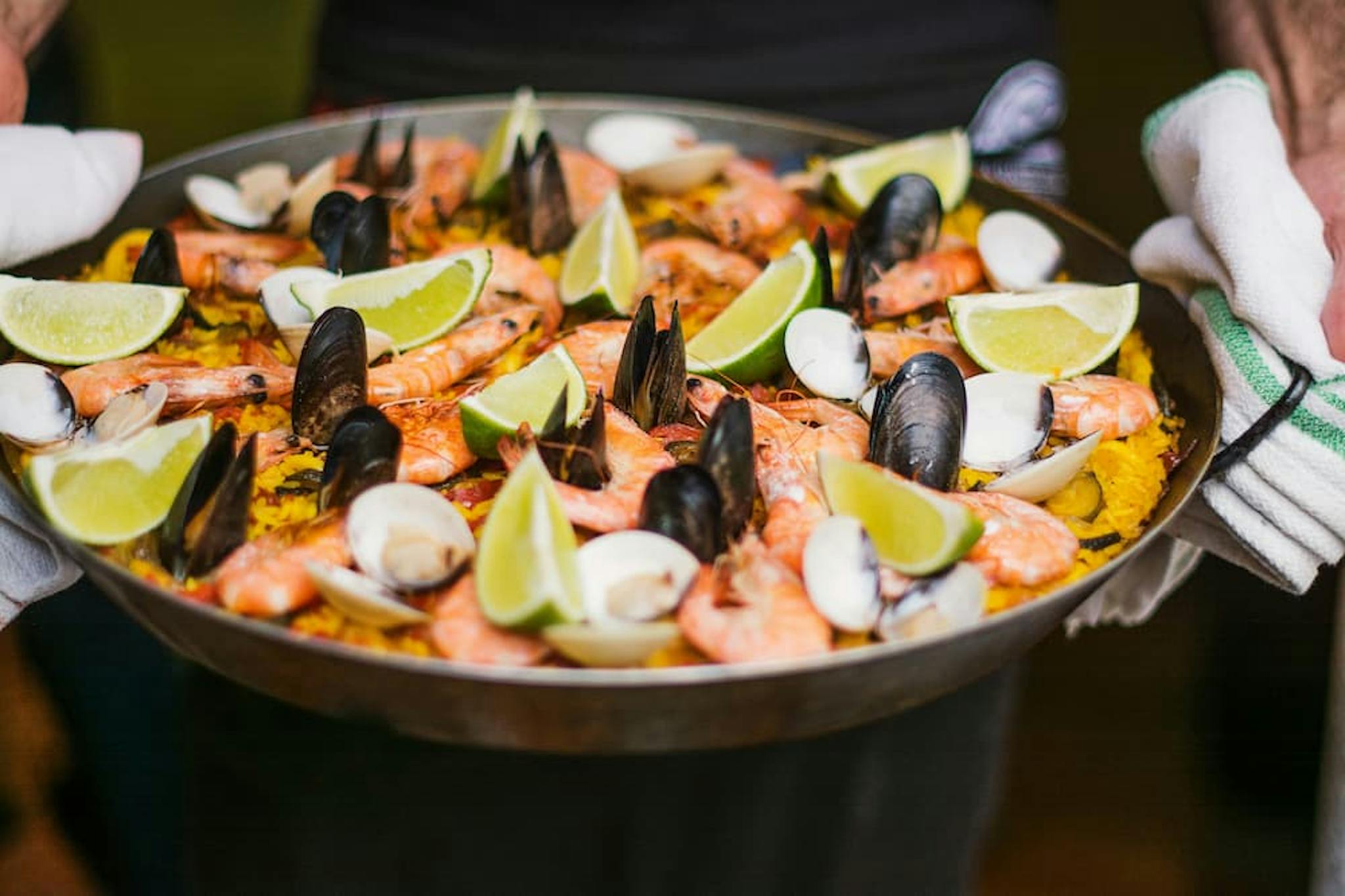 Seafood paella, including shrimp, mussels, and lemons, served on a platter