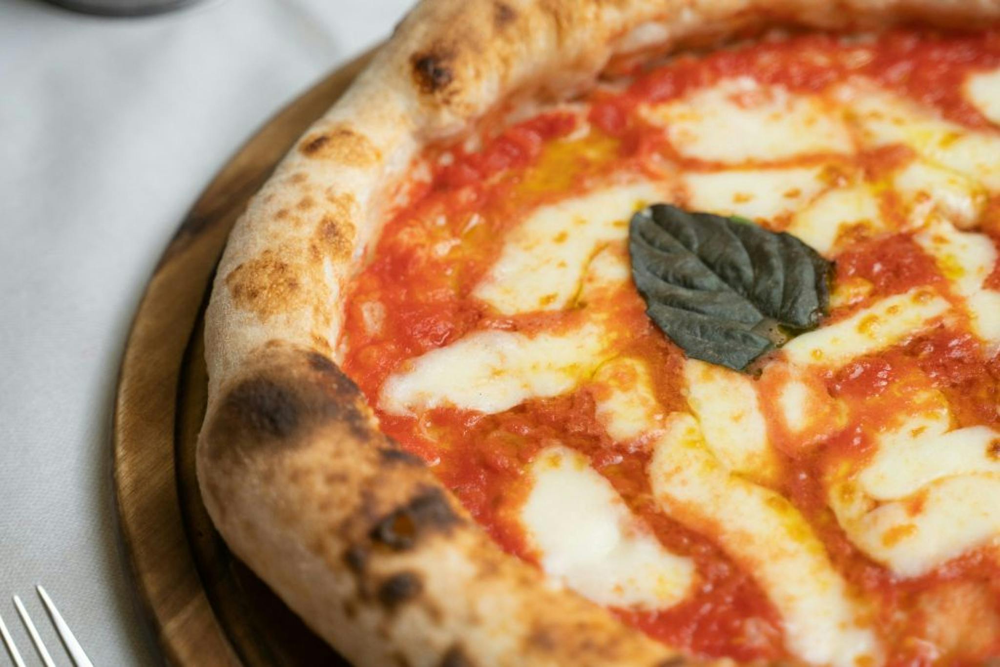 Delicious Margherita pizza with fresh tomato sauce, melted cheese, and a basil leaf, served on a wooden board