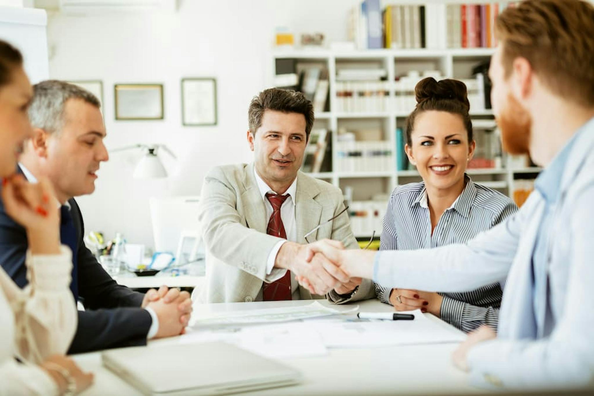 Business meeting with professionals in an office, highlighting a handshake between partners