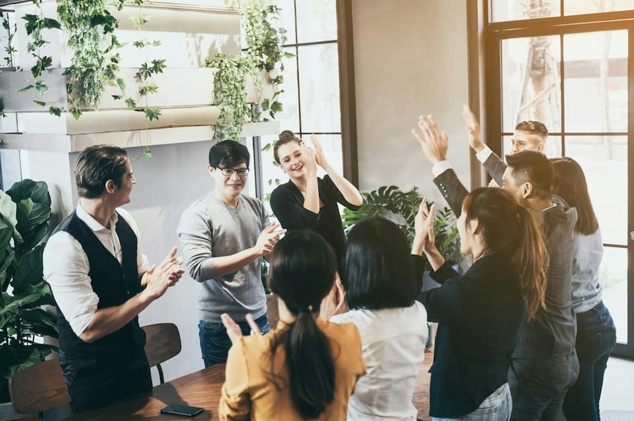 A group of people celebrating in a collaborative environment with plants in the background