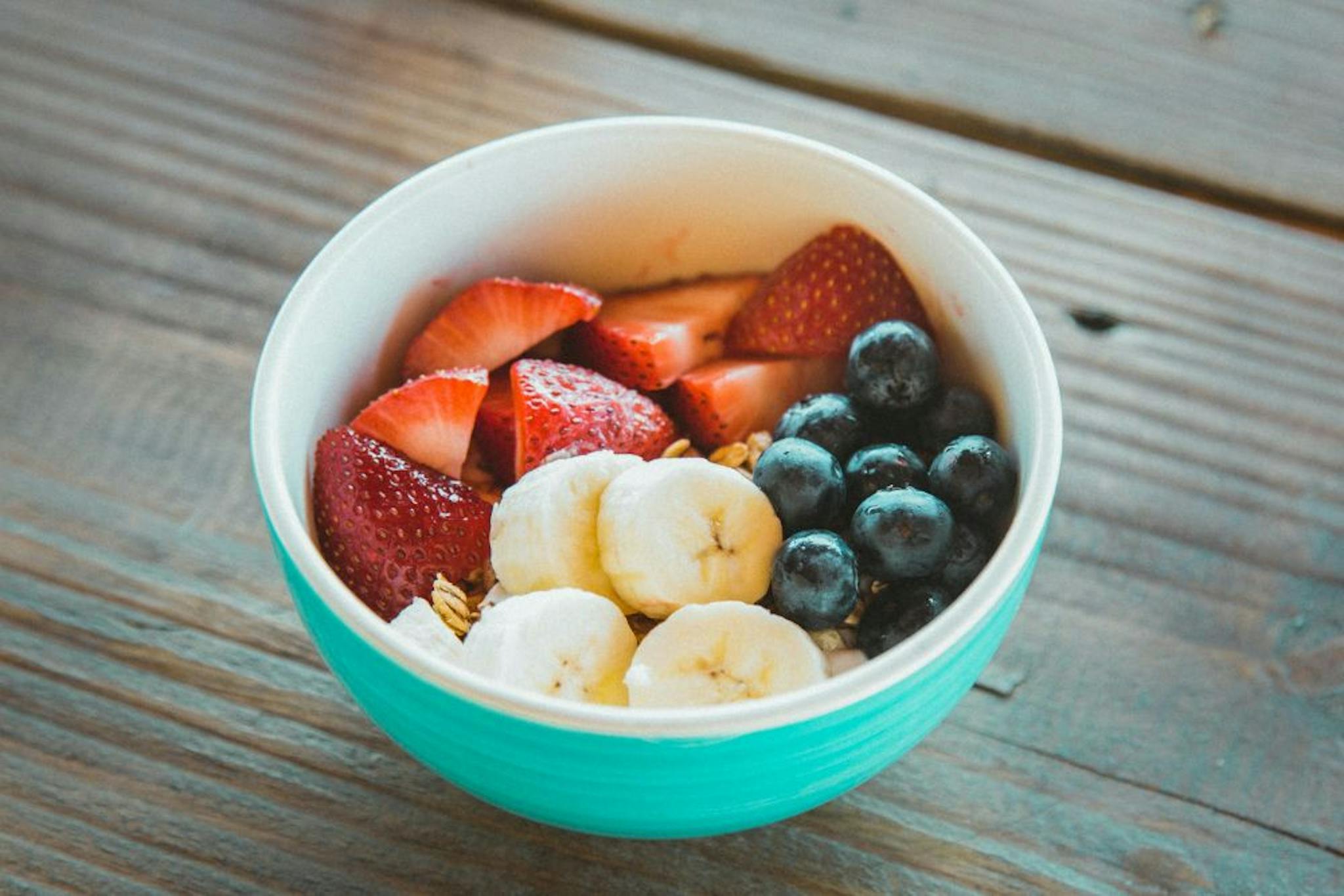 A colorful bowl with fresh fruits including strawberries, bananas, and blueberries