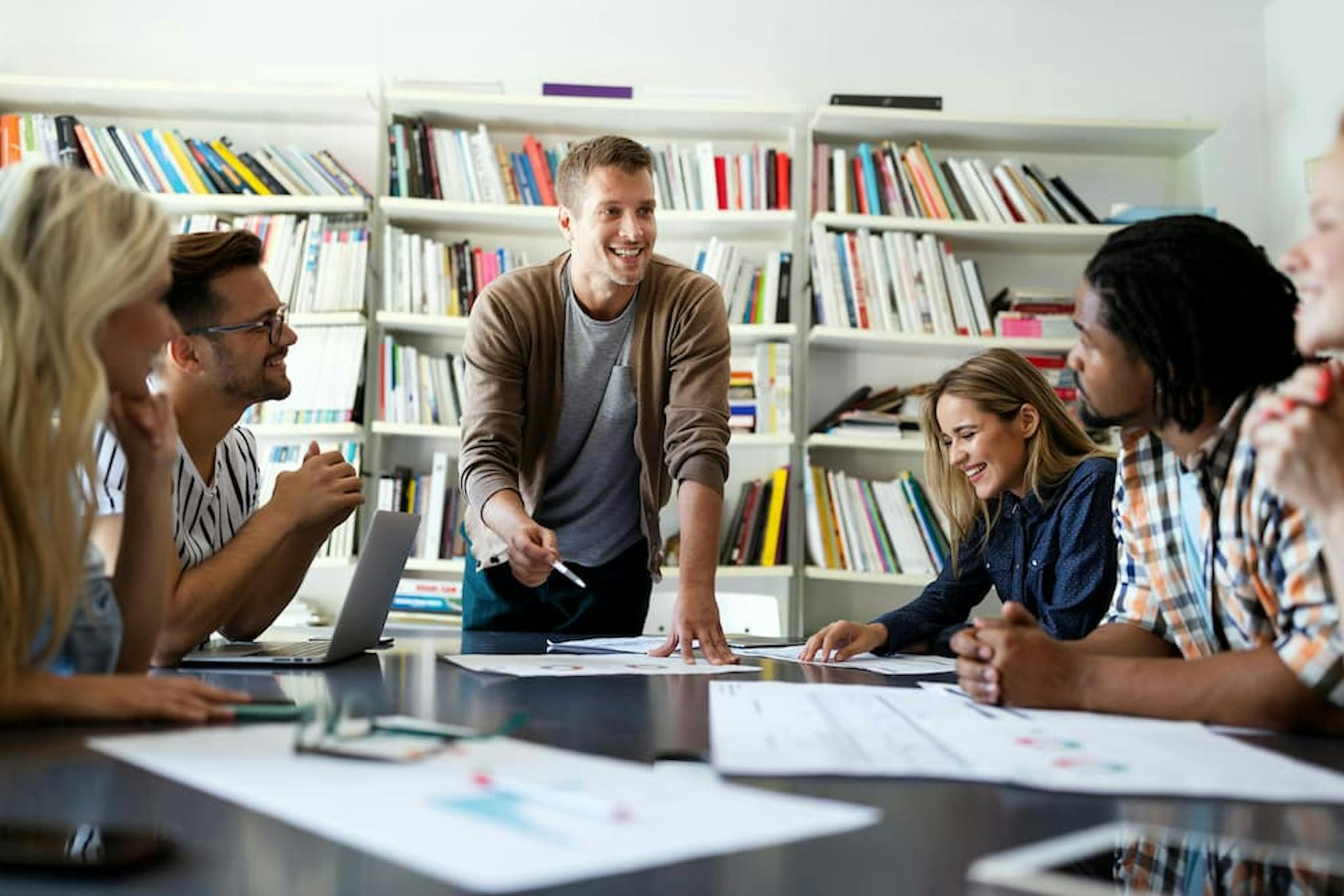 Diverse group of people collaborating in a creative meeting, with planning papers and a work environment