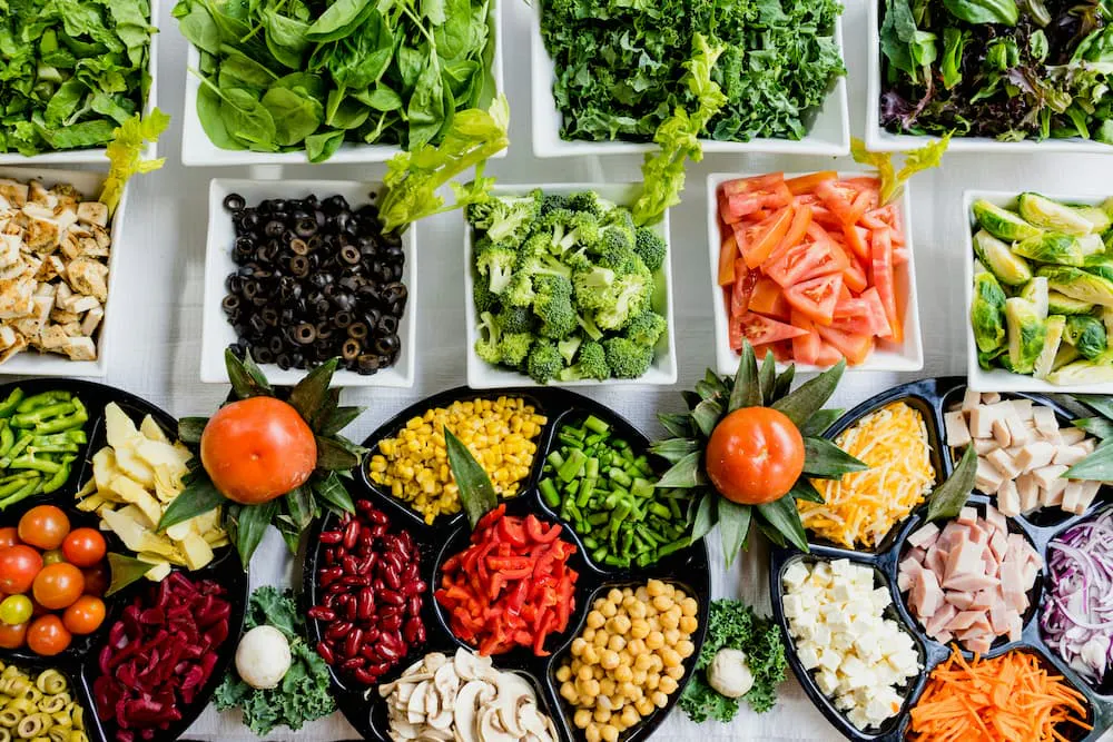 Salad with a variety of fresh vegetables such as spinach, broccoli, carrot, and tomato in different dishes, ideal for healthy eating