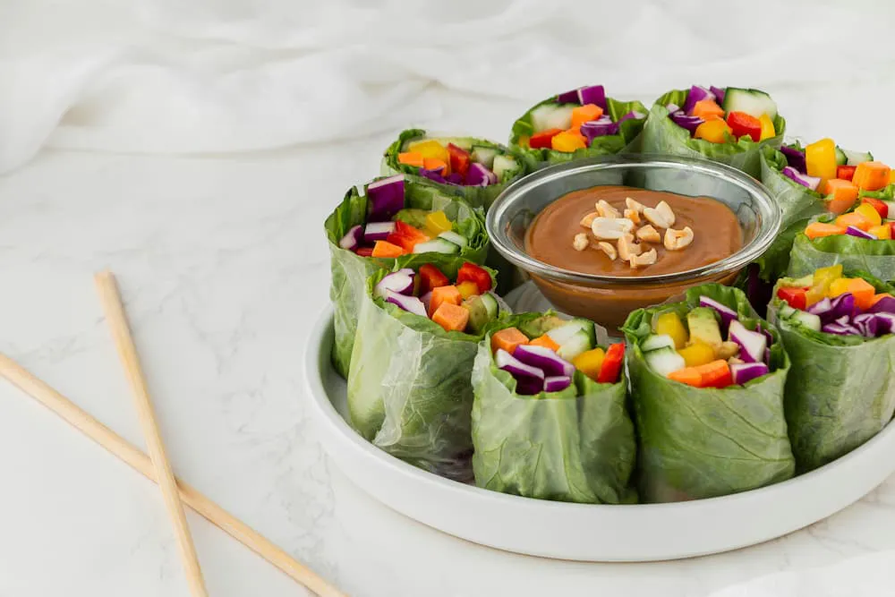 Dish with fresh vegetable rolls, served with peanut sauce in a small bowl