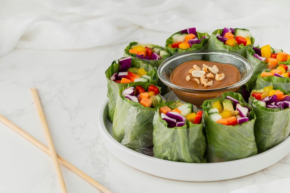 Dish with fresh vegetable rolls, served with peanut sauce in a small bowl