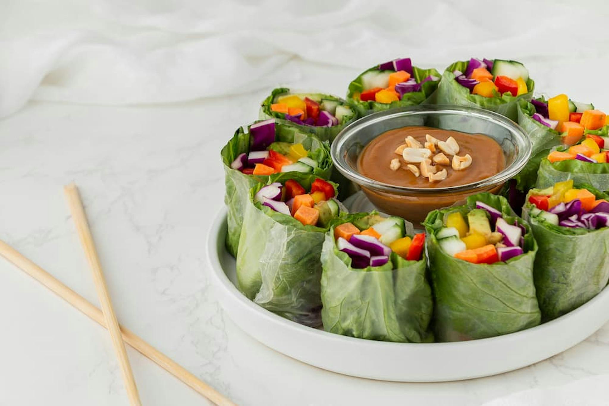 Dish with fresh vegetable rolls, served with peanut sauce in a small bowl