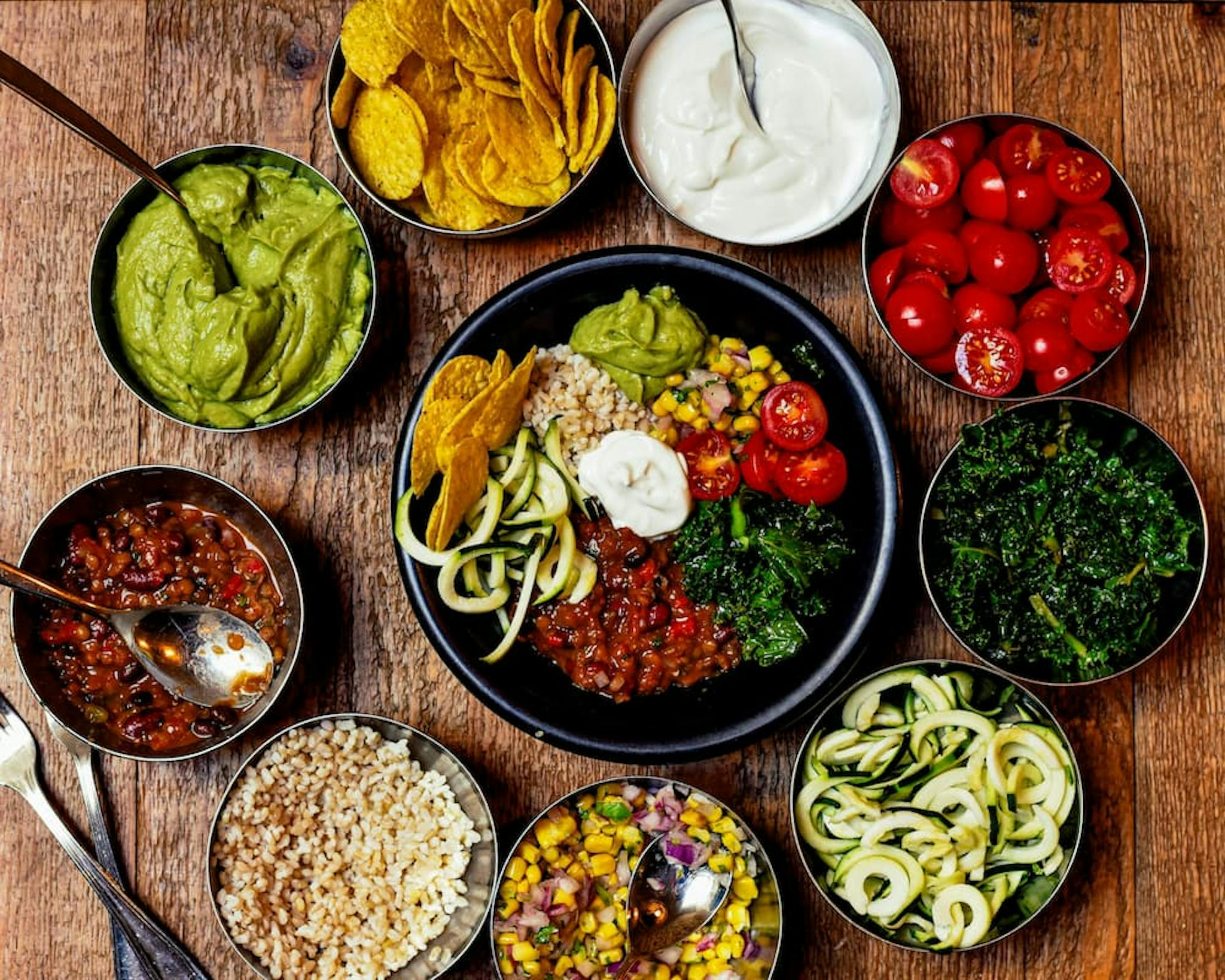 Colorful meal with guacamole, salsa, fresh vegetables, grains, and nachos