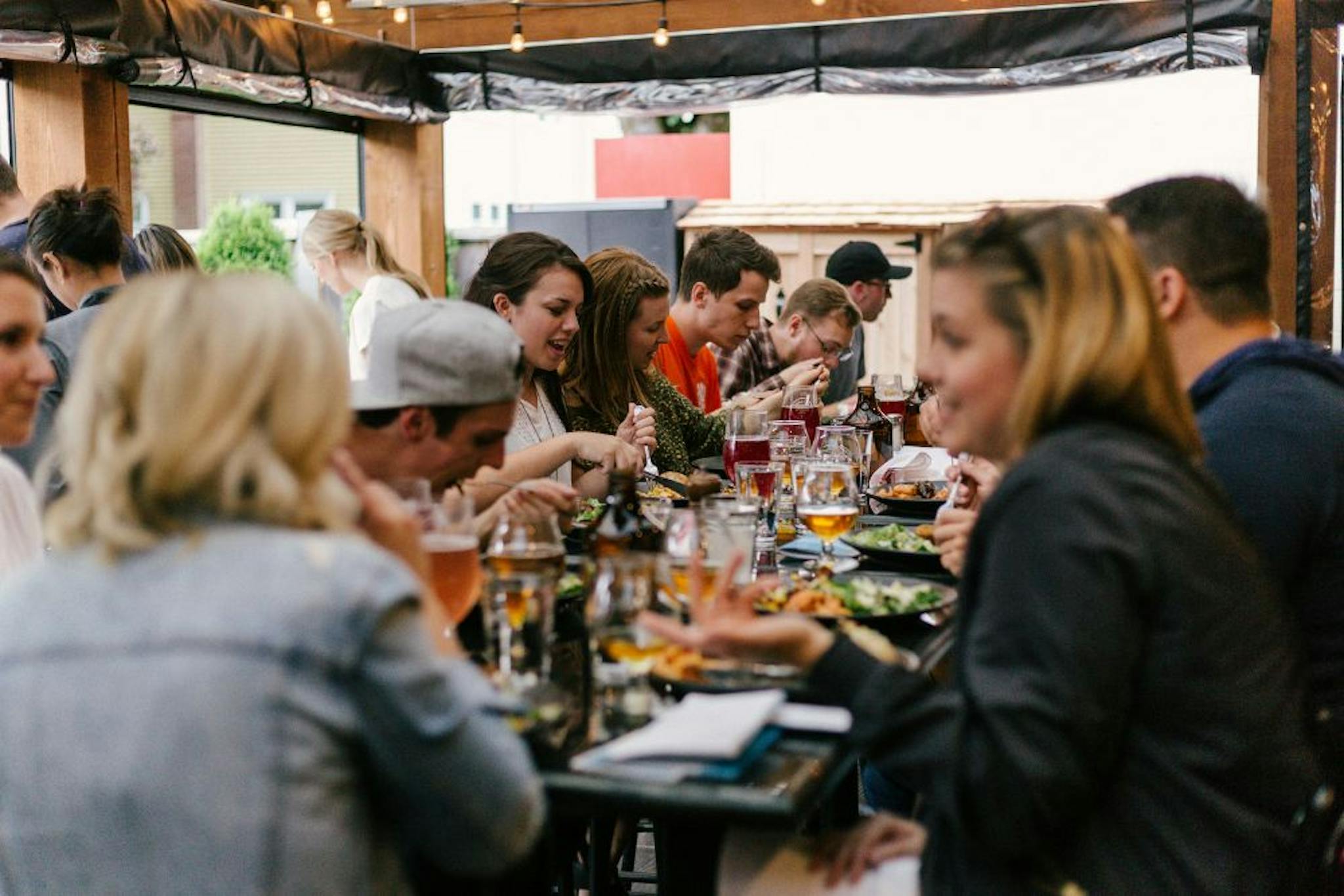 Group of people enjoying an outdoor lunch, sharing dishes and drinks in a relaxed setting