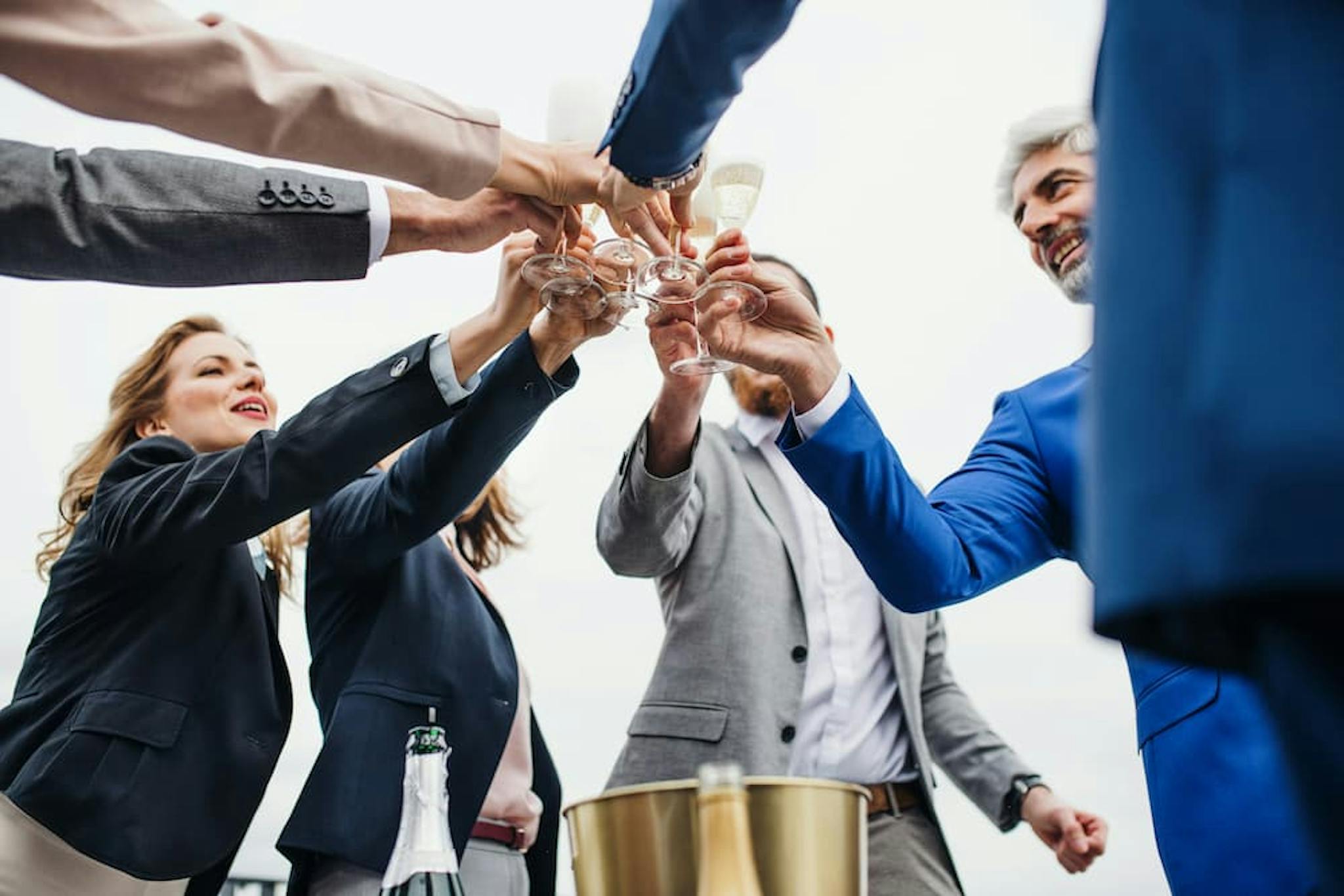 Group of people toasting to celebrate an achievement with champagne glasses.