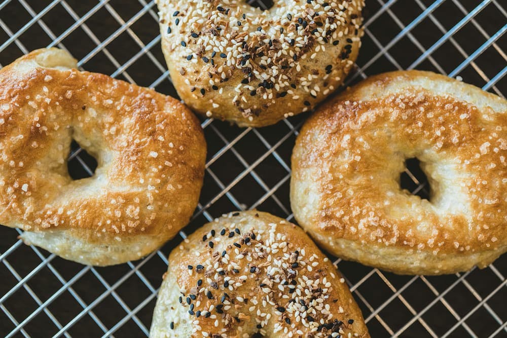 Delicious crispy bagels on a metal rack, with different sesame and sugar toppings.
