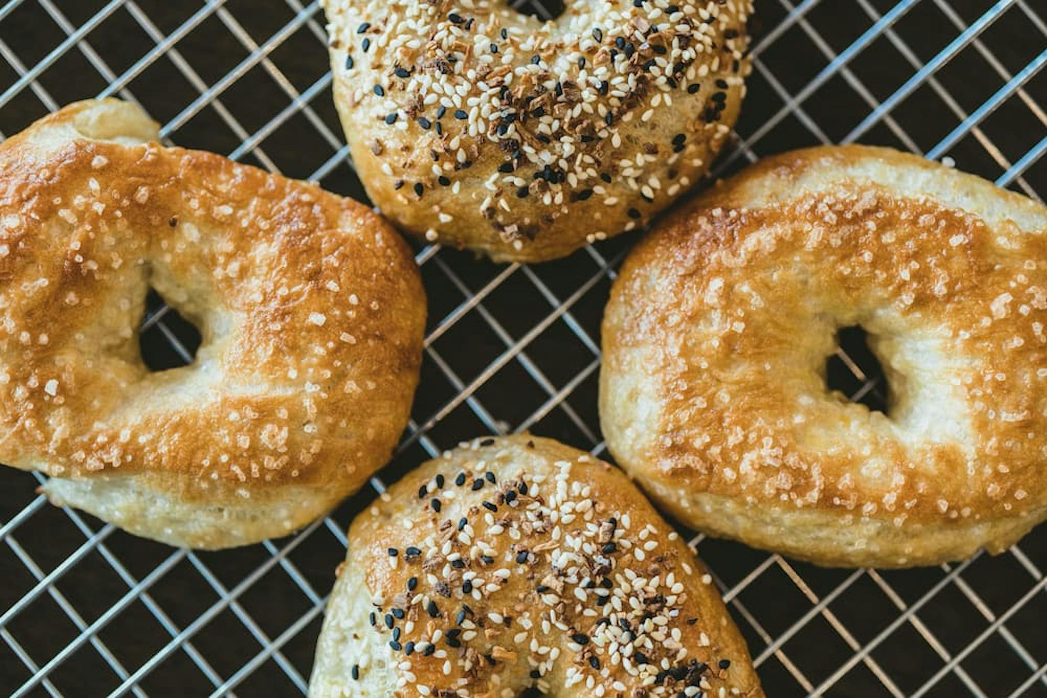 Delicious crispy bagels on a metal rack, with different sesame and sugar toppings.