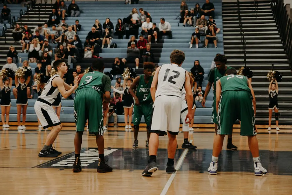 Basketball players in a close game, getting ready for the shot. The crowd, with fans and cheerleaders, cheer on the sporting event