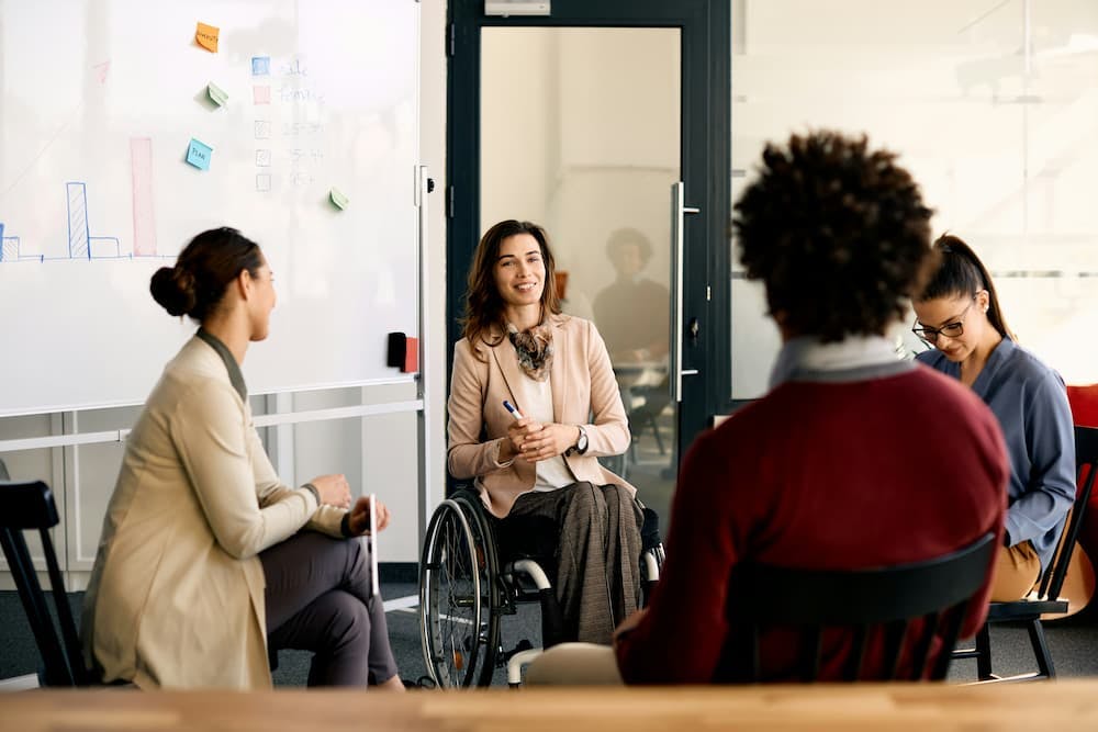 Collaborative meeting of professionals with a woman in a wheelchair leading the discussion