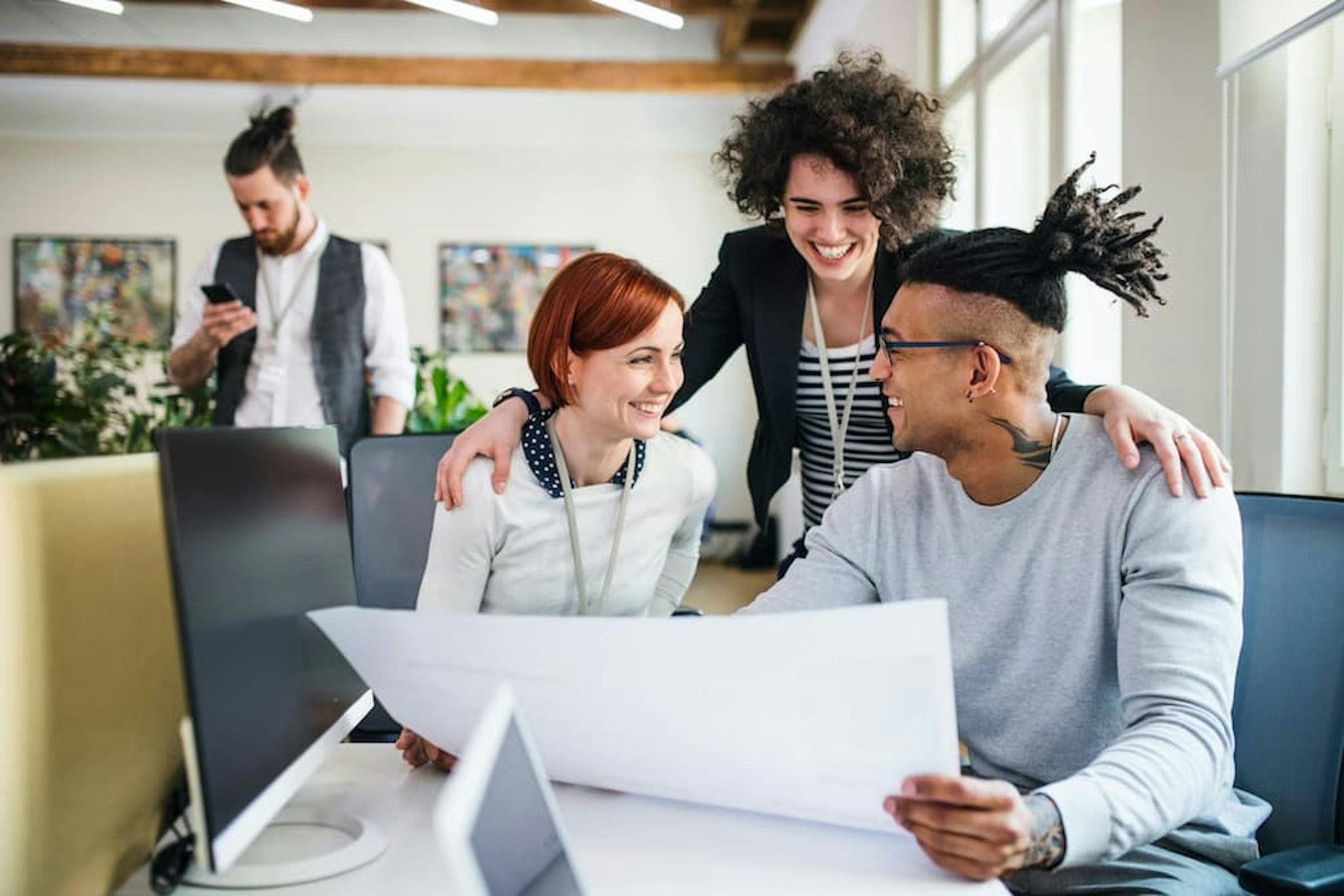 Group of professionals collaborating in a modern work environment, smiling and discussing ideas while exchanging Valentine's Day cards.