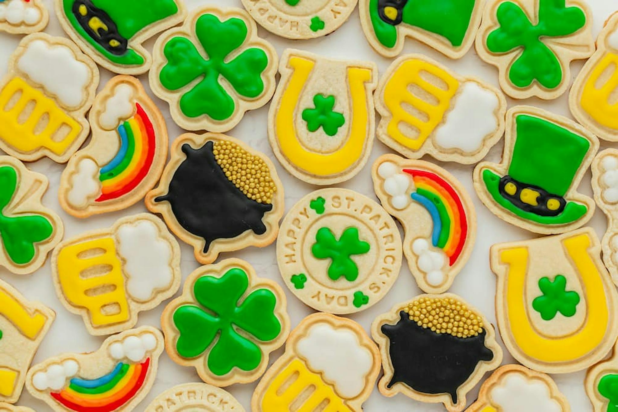 Decorated cookies with St. Patrick's Day themes, including shamrocks, hats, and pots of gold, in vibrant colors like green and yellow.