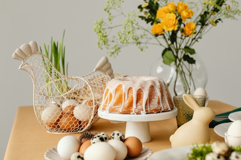 Table decorated for Easter with cake, various eggs, and flowers.