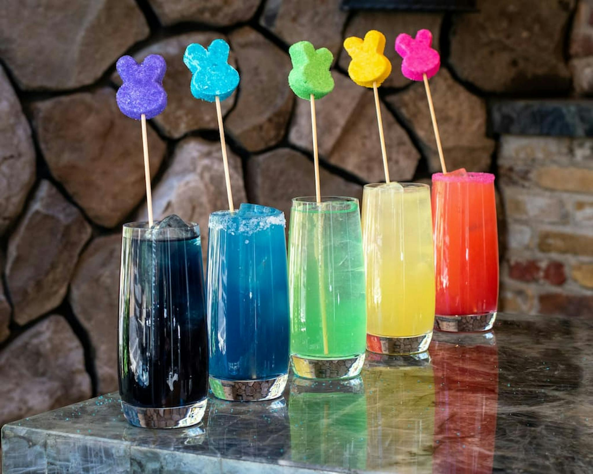 Colorful cocktails with rabbit-shaped decorations on a stone background.