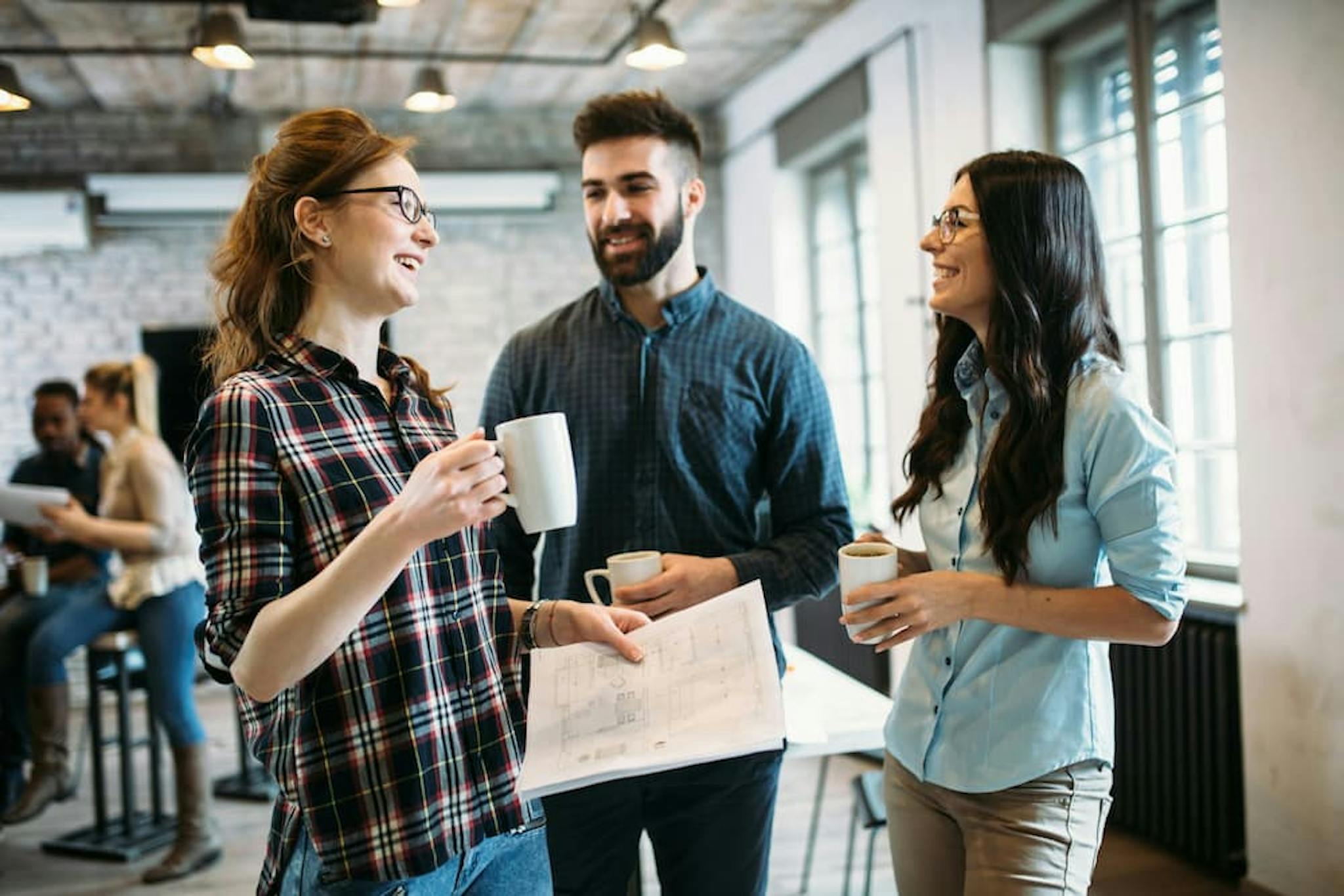 A group of colleagues gathered in a modern office space, engaging in a casual conversation.