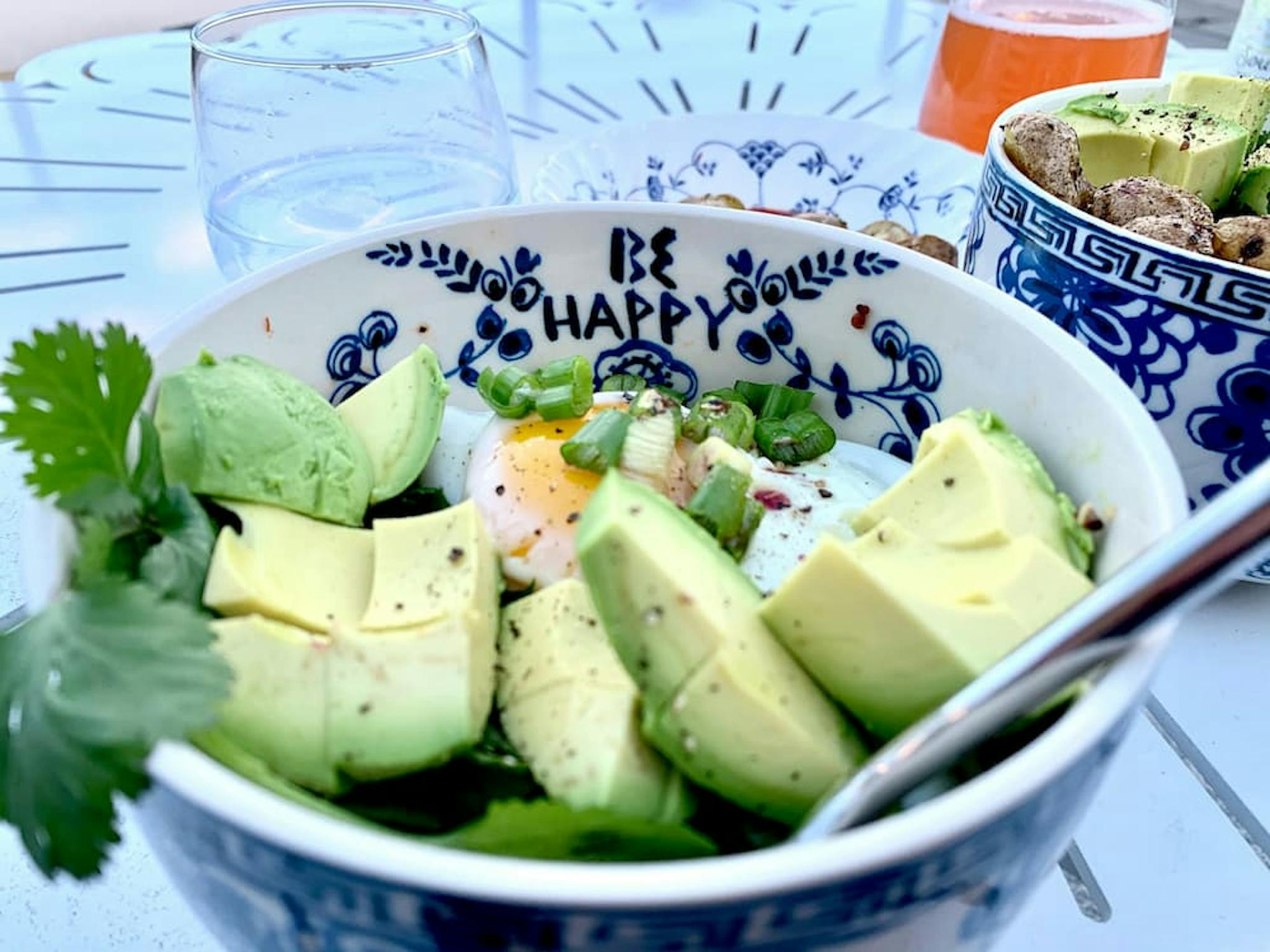 Colorful bowl with avocado, egg, and fresh seasonings.