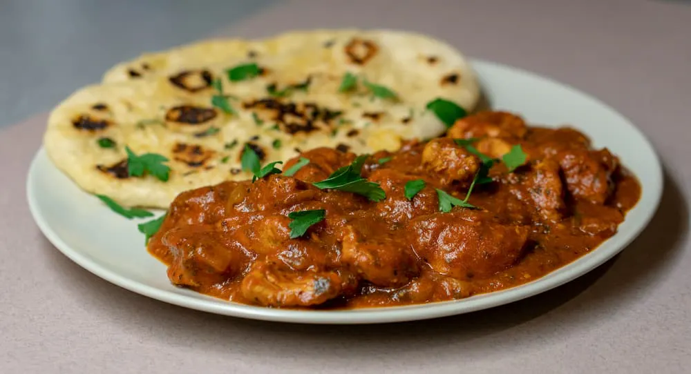 Combination of curry and naan, garnished with fresh herbs