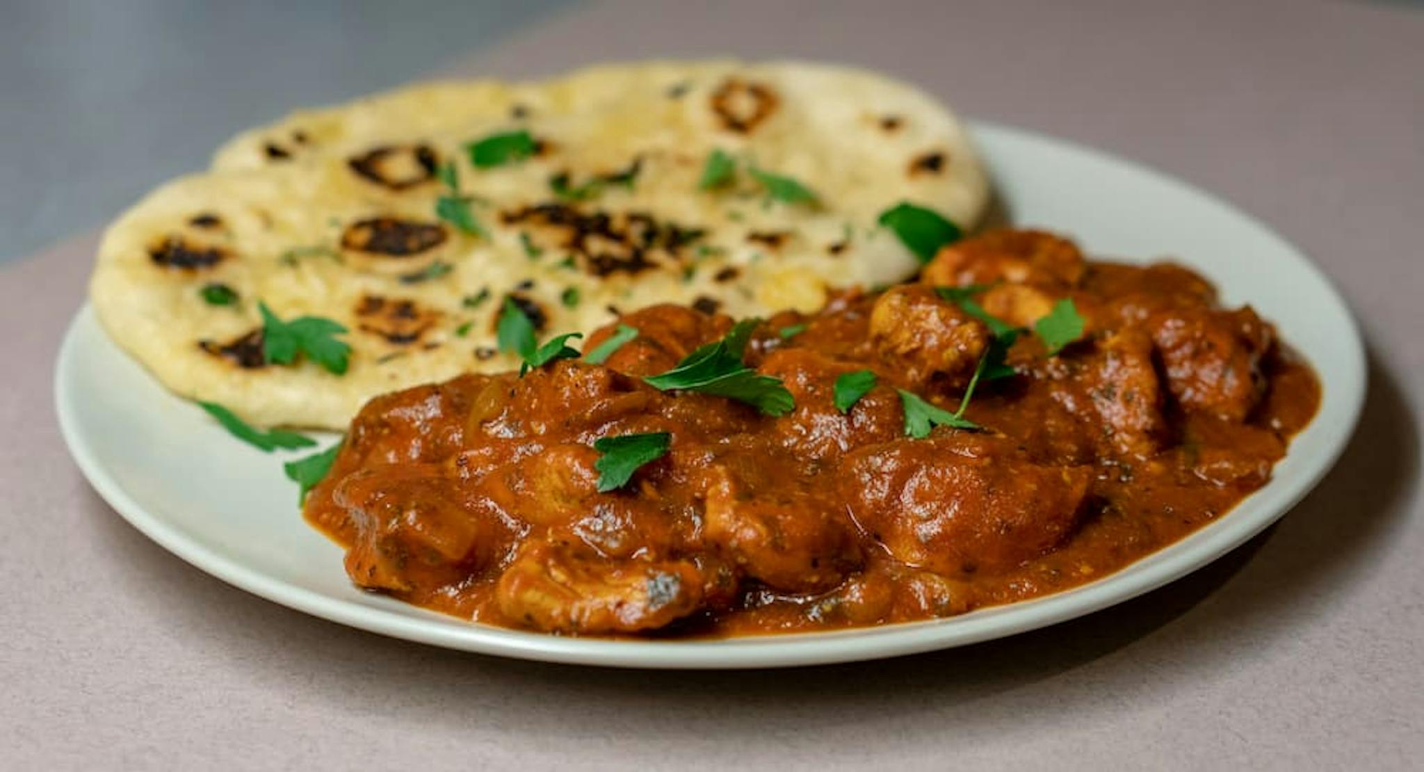 Combination of curry and naan, garnished with fresh herbs