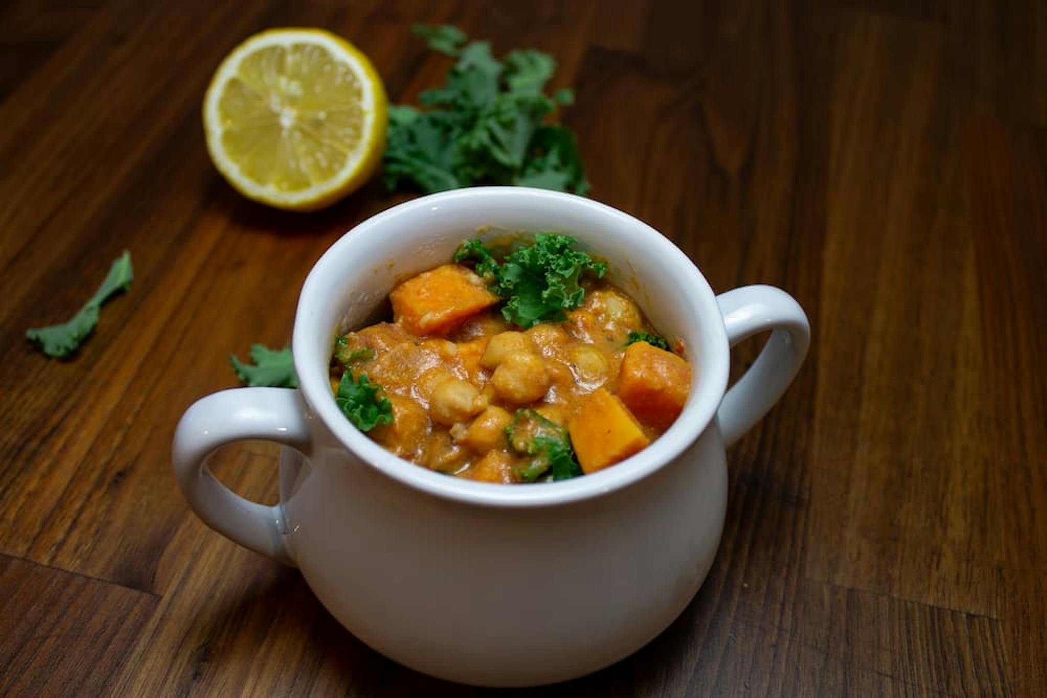 Japanese curry served in a white bowl, garnished with lemon and green leaves.