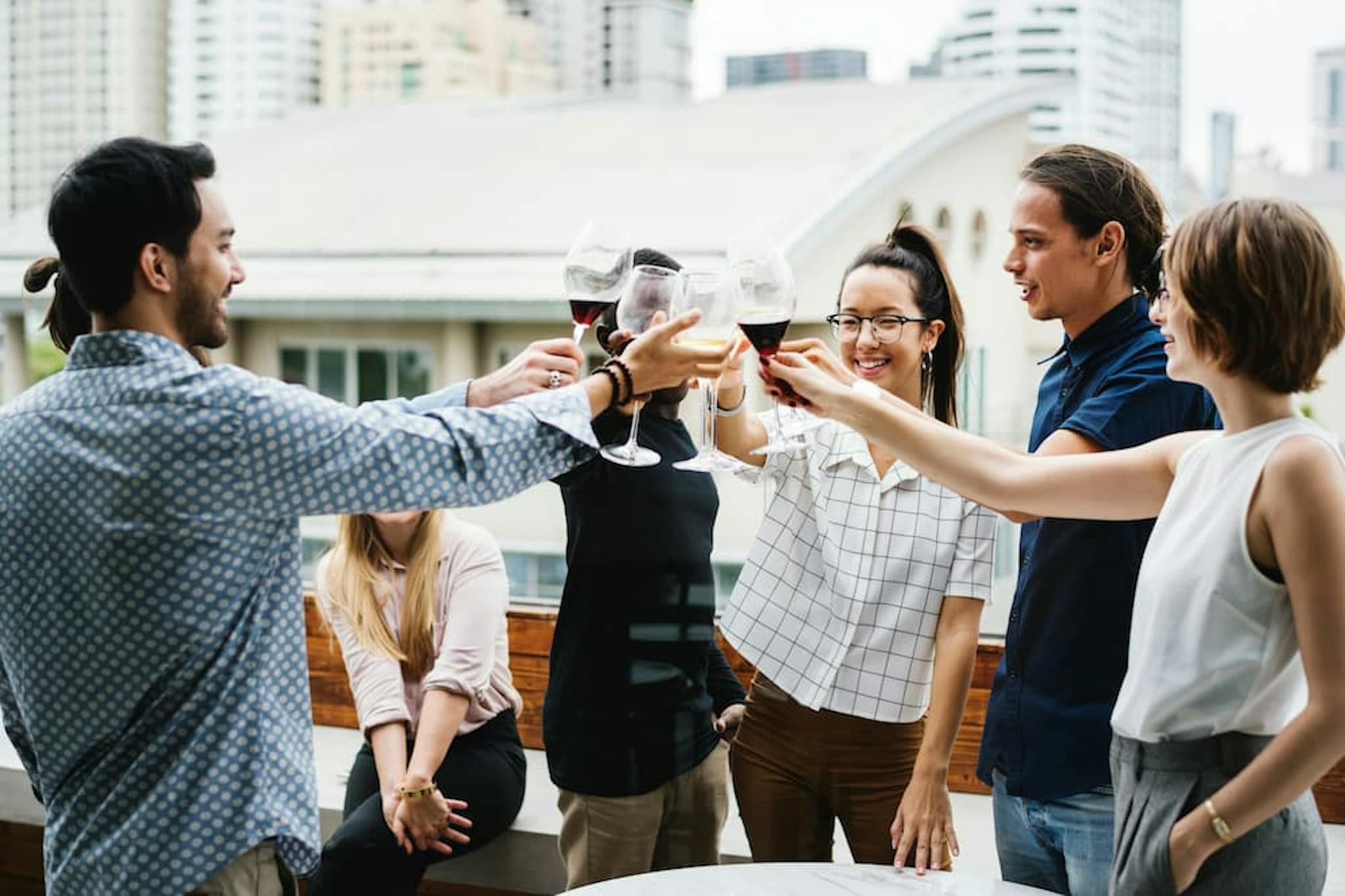 A group of friends toasting with glasses of red wine at an outdoor party.