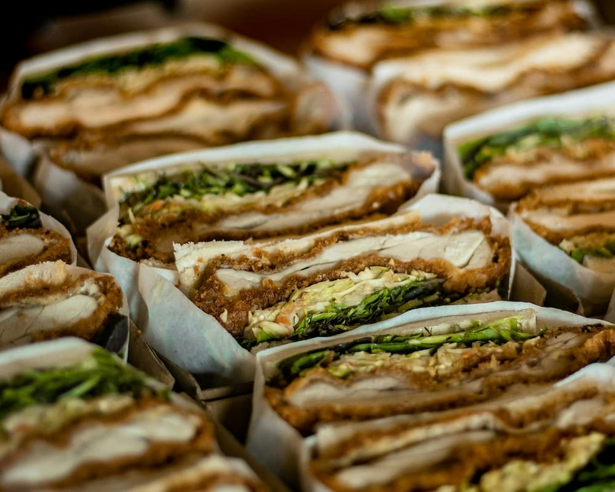 Delicious crispy chicken sandwiches, layered with lettuce and mayonnaise, wrapped in paper.