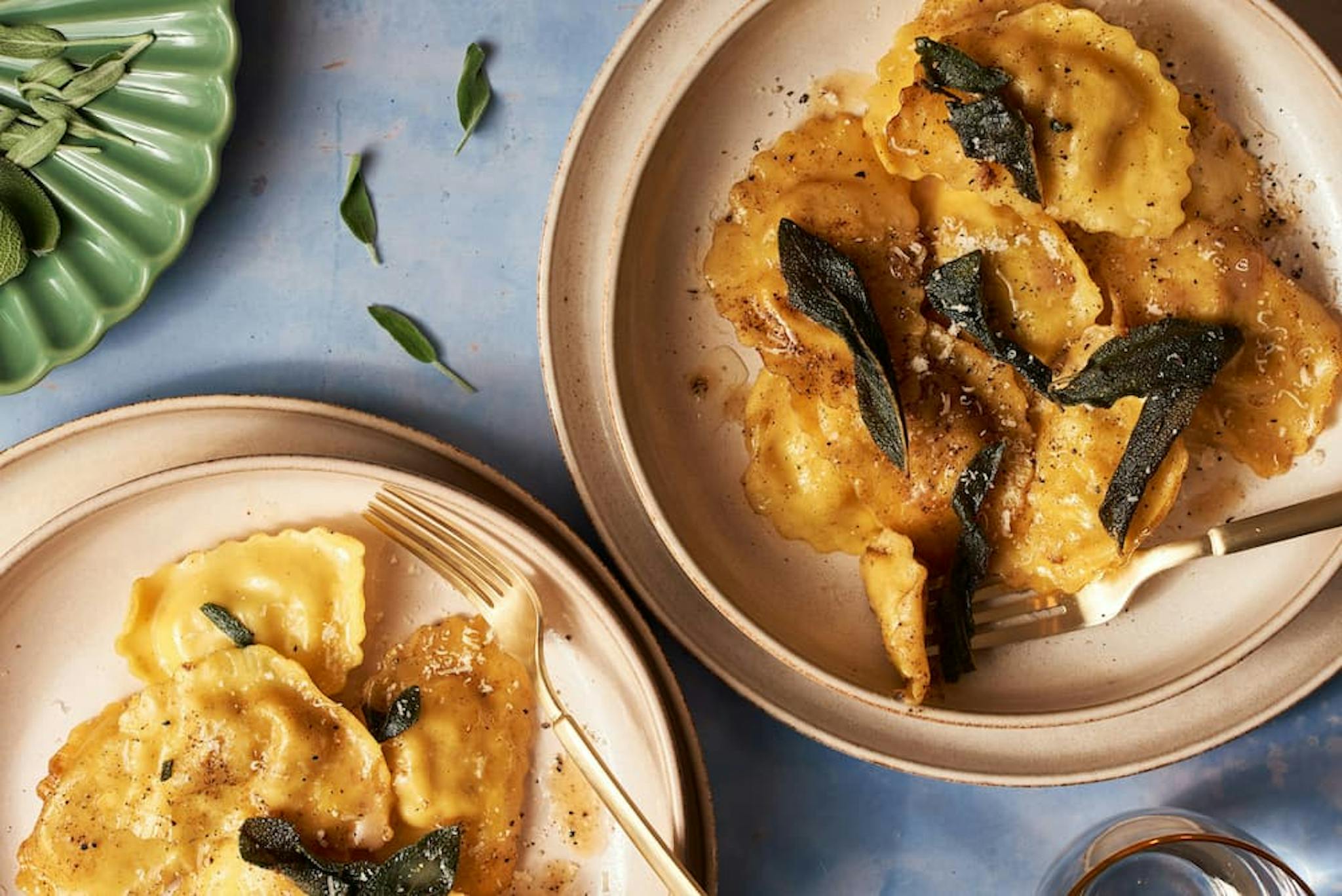 Delicious ravioli served on plates, with butter sauce and sage leaves.