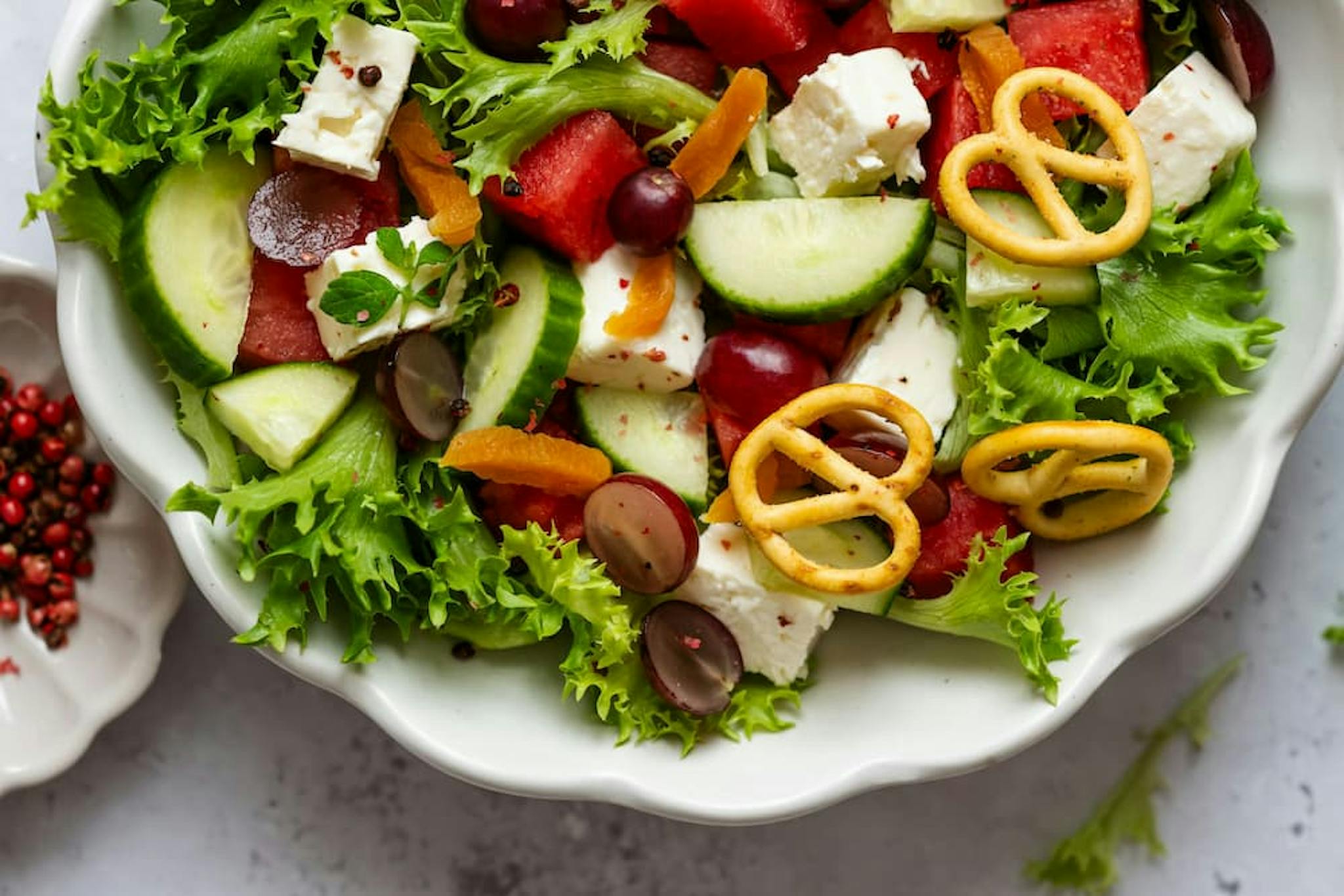 Delicious summer salad with watermelon, grapes, cucumber, feta cheese, and lettuce.