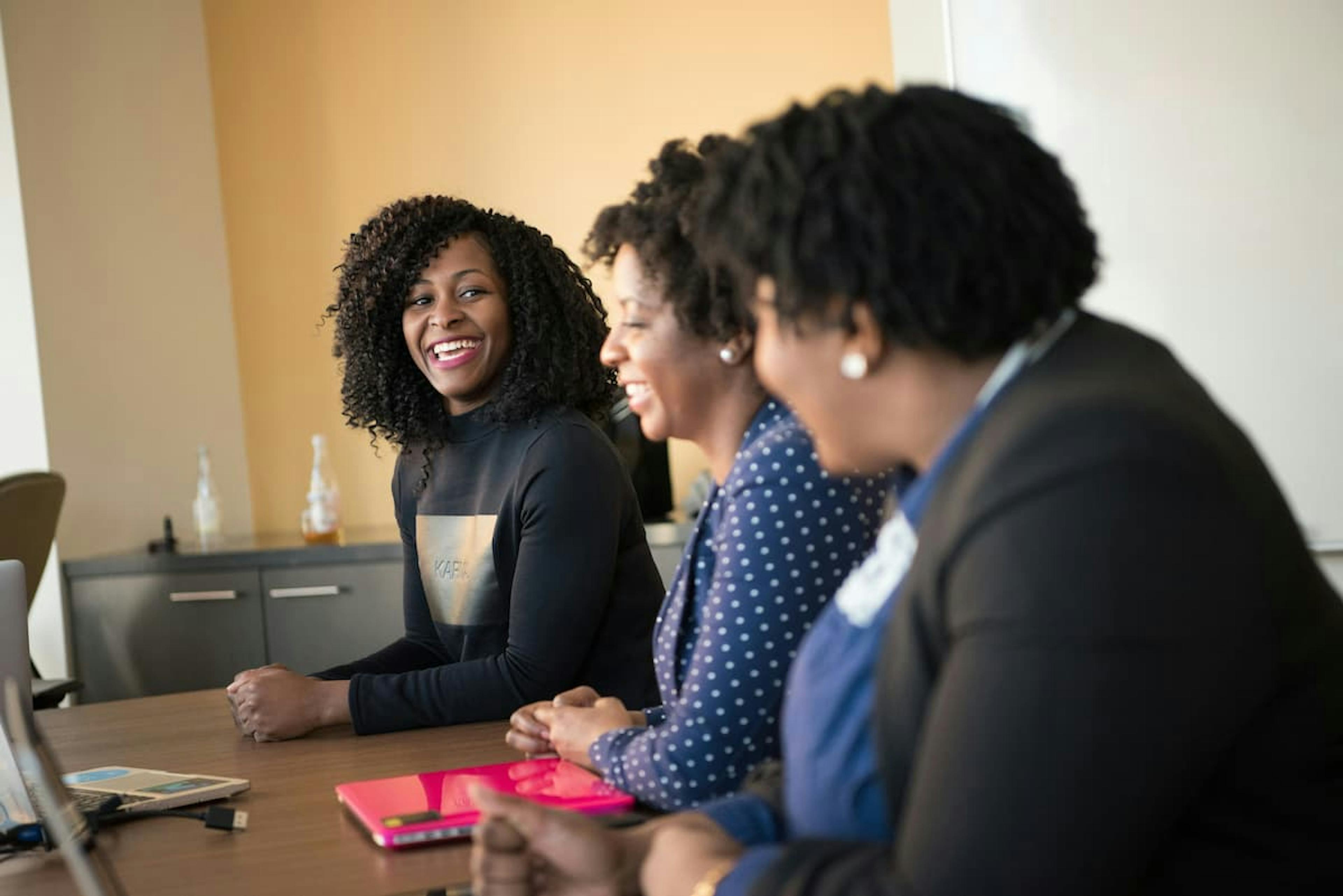 Three colleagues are talking and smiling.